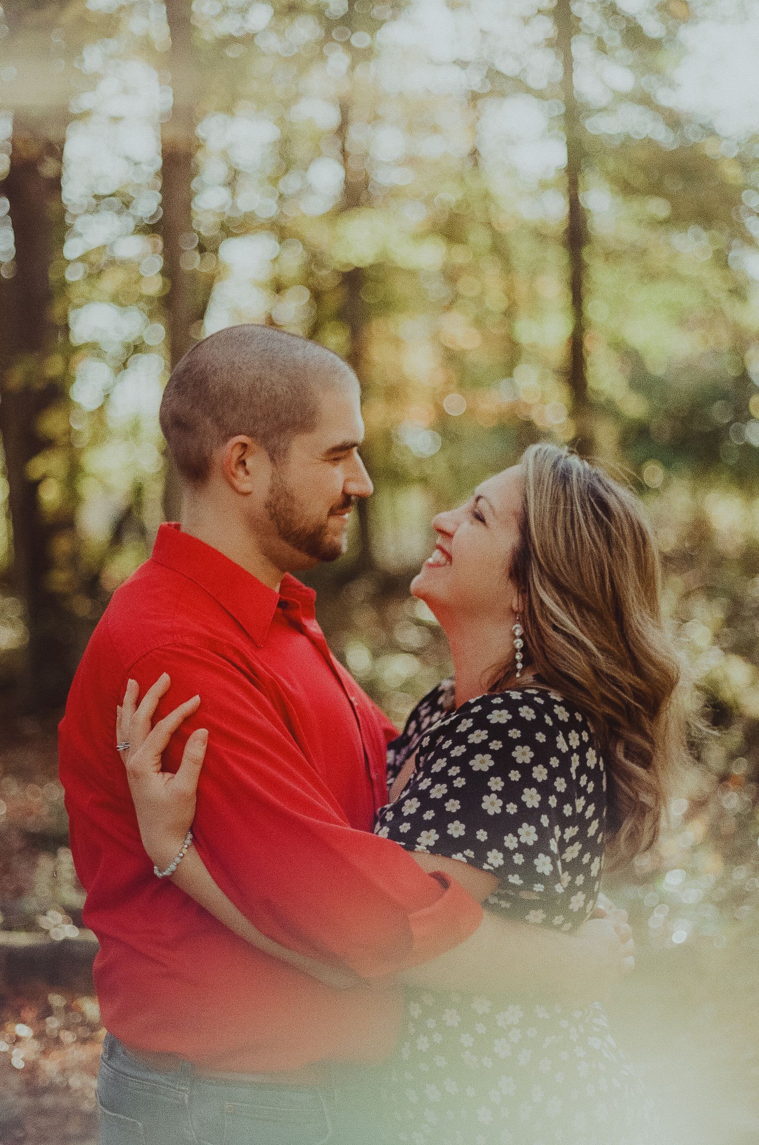 A couple in red and polka dots share joyful laughter together during an outdoor autumn photoshoot.