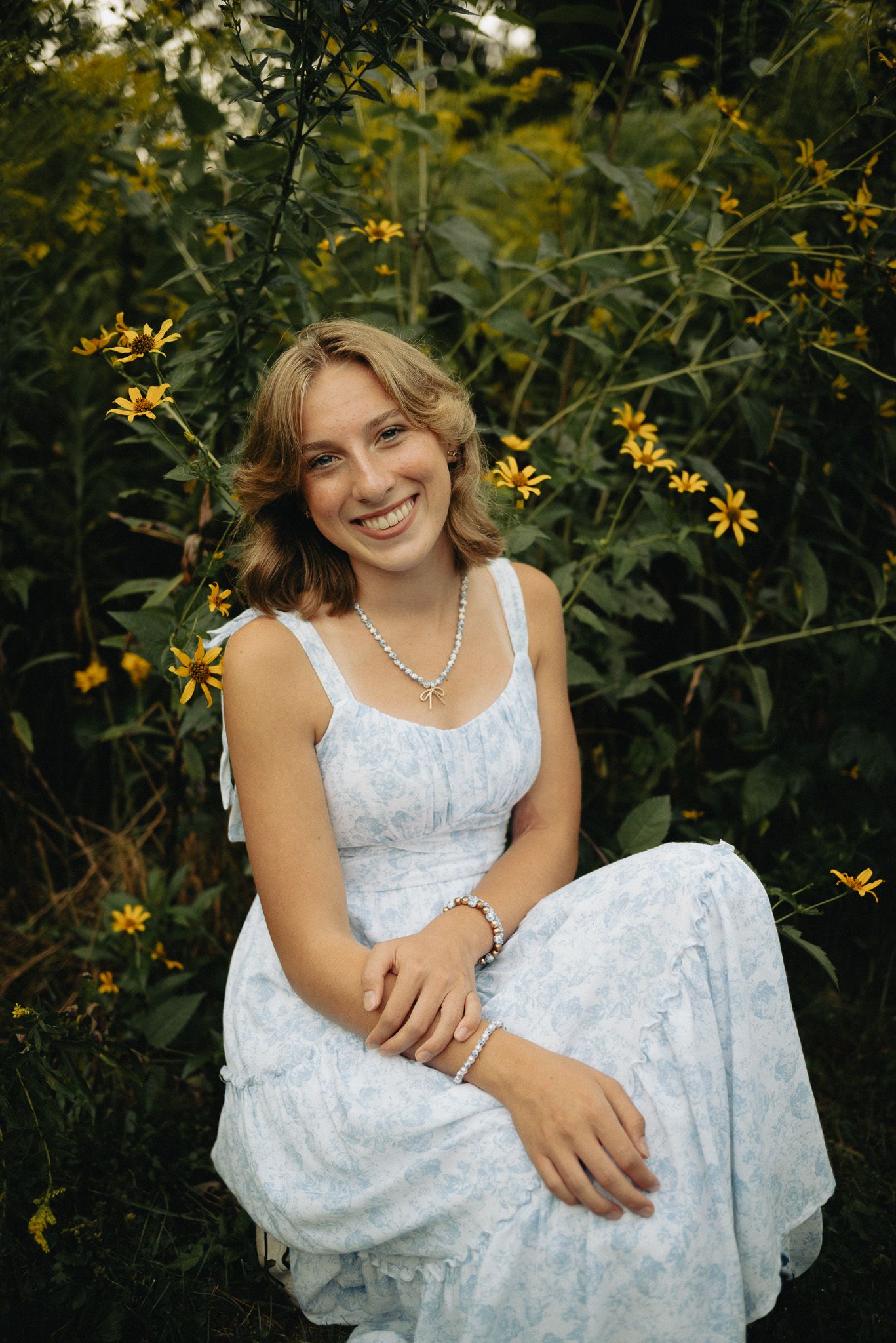 A white sundress contrasts beautifully with yellow wildflowers in a natural garden setting.
