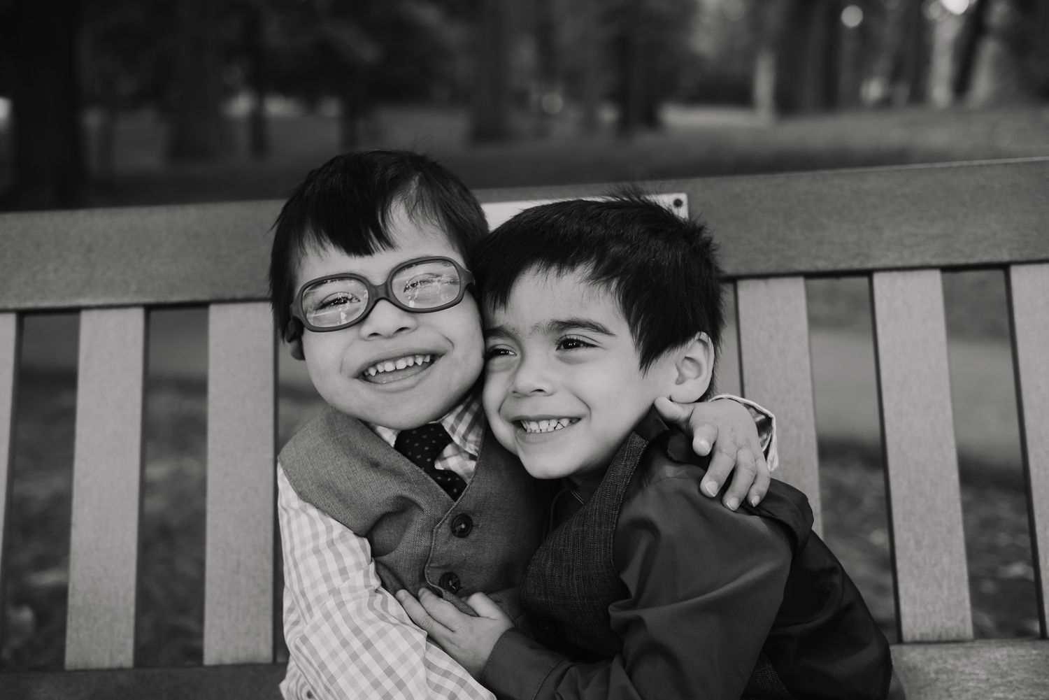 Black and white photo of children laughing together on a bench.