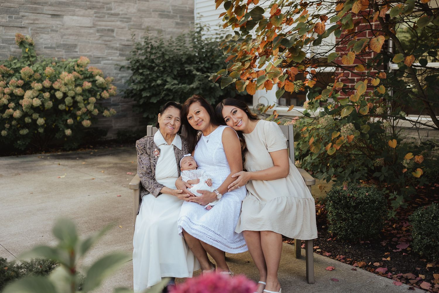 A family group wearing white sits together in a garden setting.