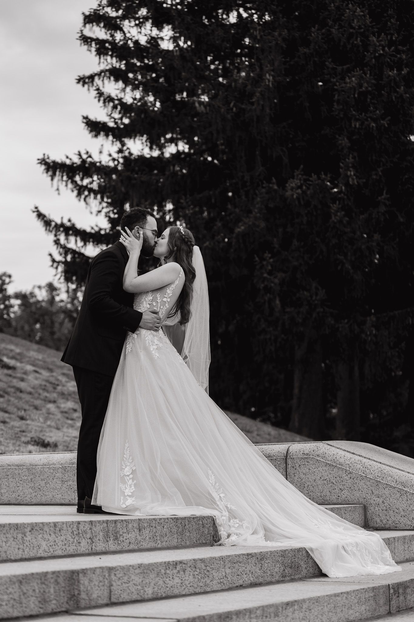 Elegant wedding couple poses on stone steps during their outdoor photo session.