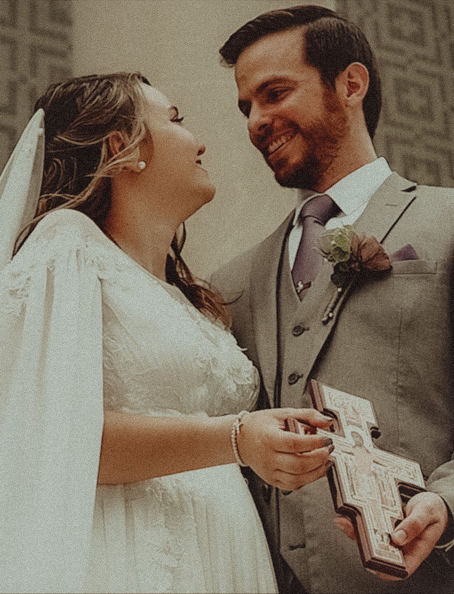Bride in white dress and groom in grey suit exchange gifts during their wedding ceremony.