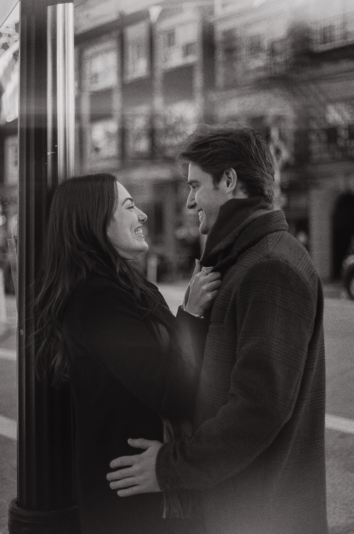 A romantic black and white photo sequence showing a couple embracing and leaning in for a kiss on a city street.