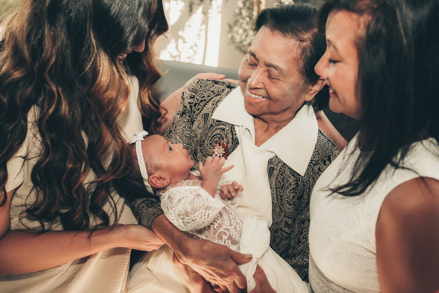 A joyful multigenerational family moment as they admire a newborn baby together.