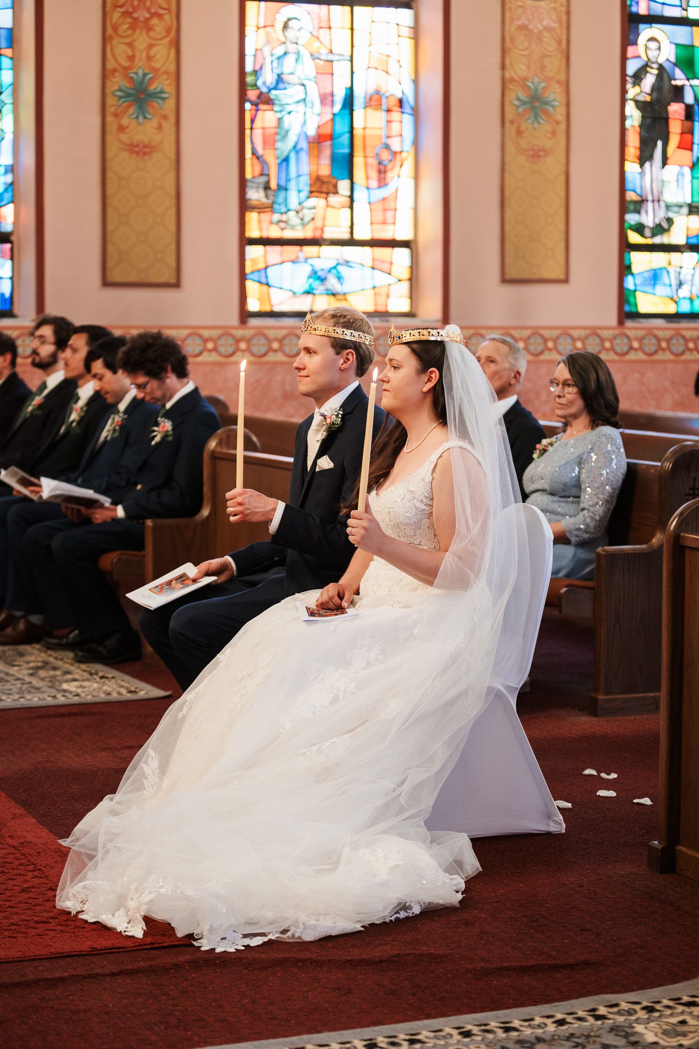 Bride in flowing white gown seated during traditional church ceremony.