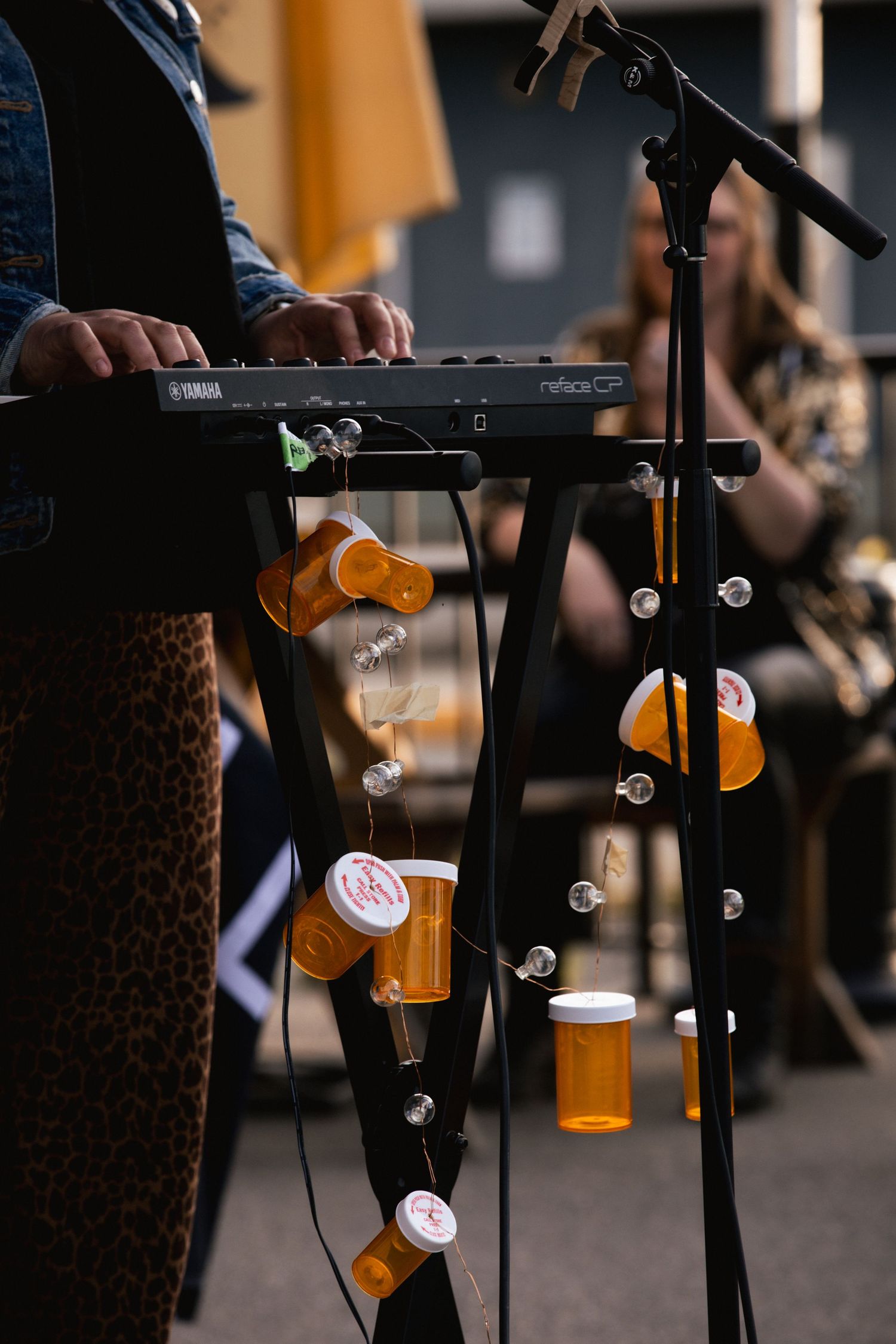 Prescription pill bottles hanging decoratively from a microphone stand near a Yamaha keyboard.
