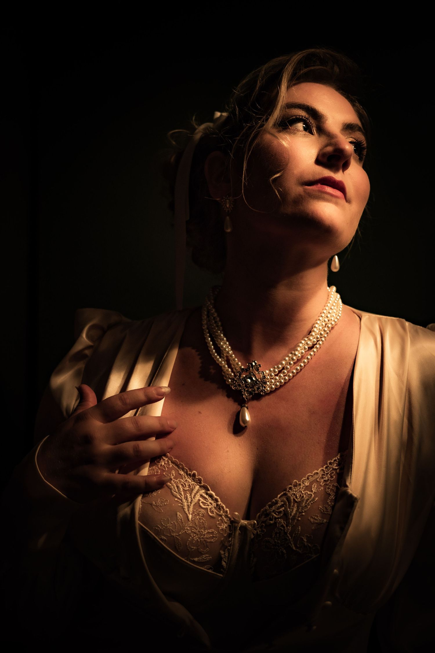 Portrait en clair-obscur d'une femme éclairée par une lumière latérale, dans une ambiance cinématographique.