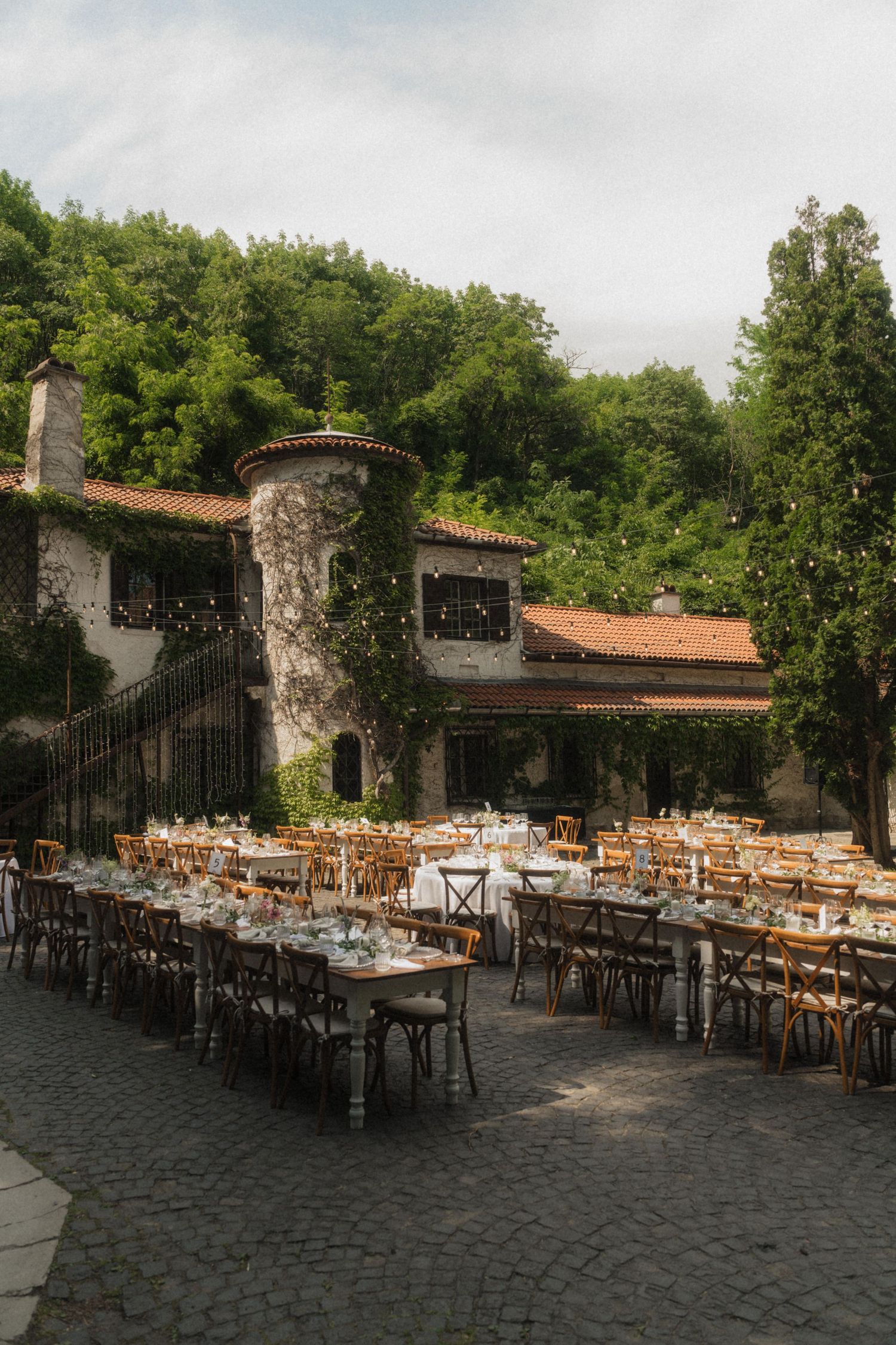 Elegant outdoor wedding reception setup in rustic stone villa courtyard with long dining tables.