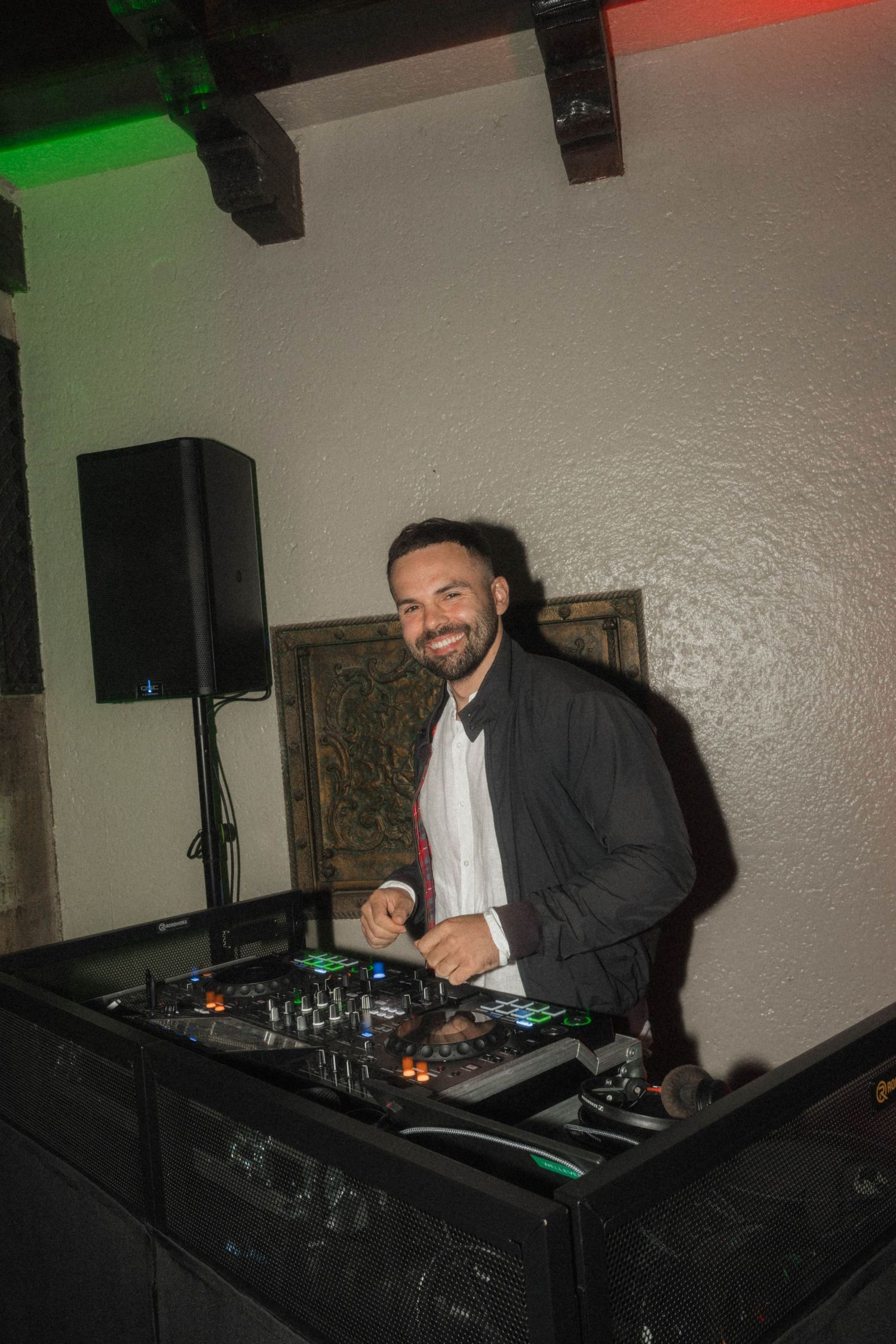 Smiling DJ at his mixing console with speakers at a wedding reception venue.