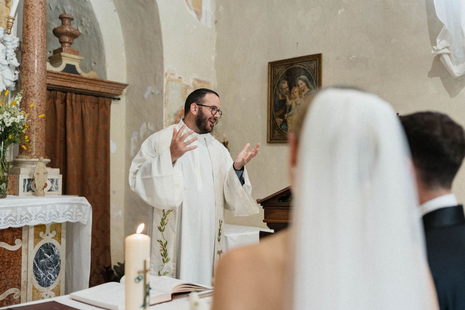 Priest officiating a wedding ceremony at church altar with bride and groom standing before him.