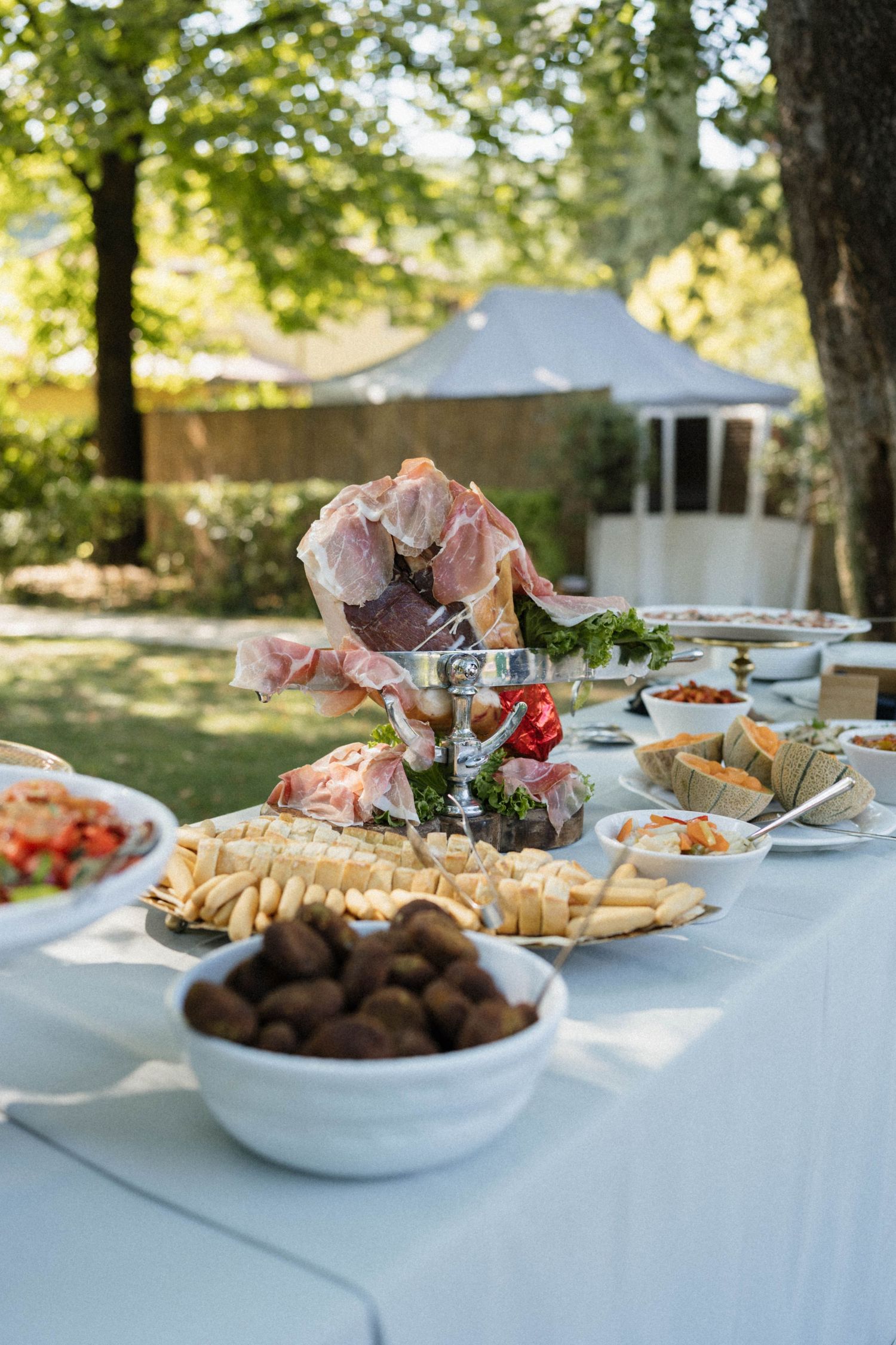 Outdoor wedding buffet table featuring charcuterie, cheese, and appetizers in a garden setting.