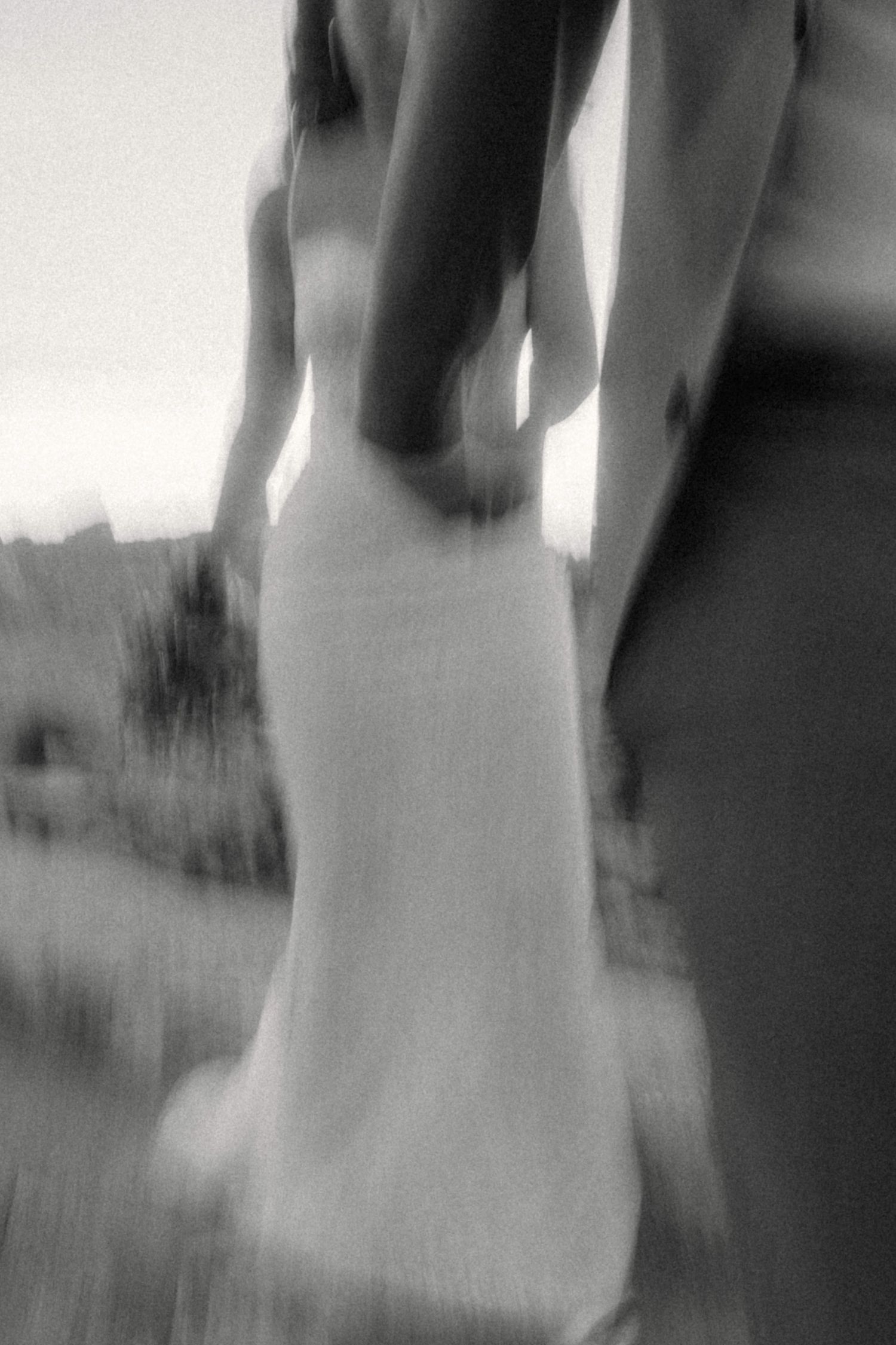 Artistic blurred black and white photo of bride and groom holding hands outdoors on their wedding day.