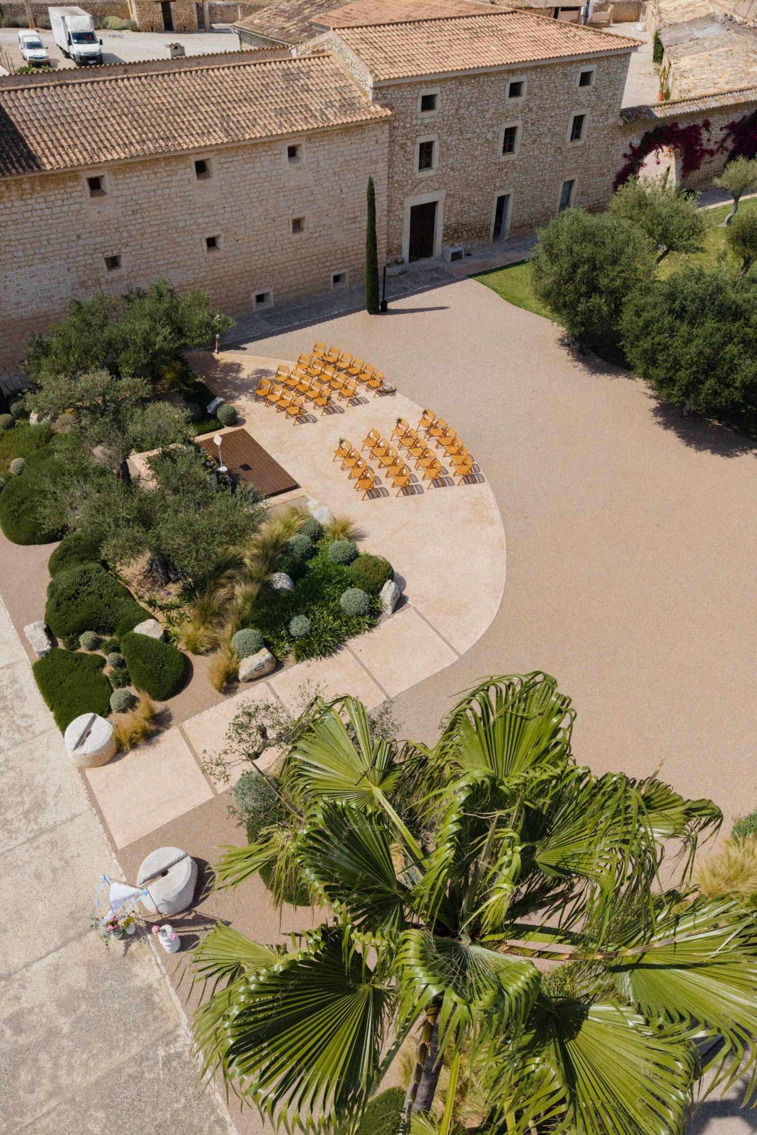 Aerial view of a rustic stone venue courtyard with yellow chairs arranged for an outdoor ceremony.