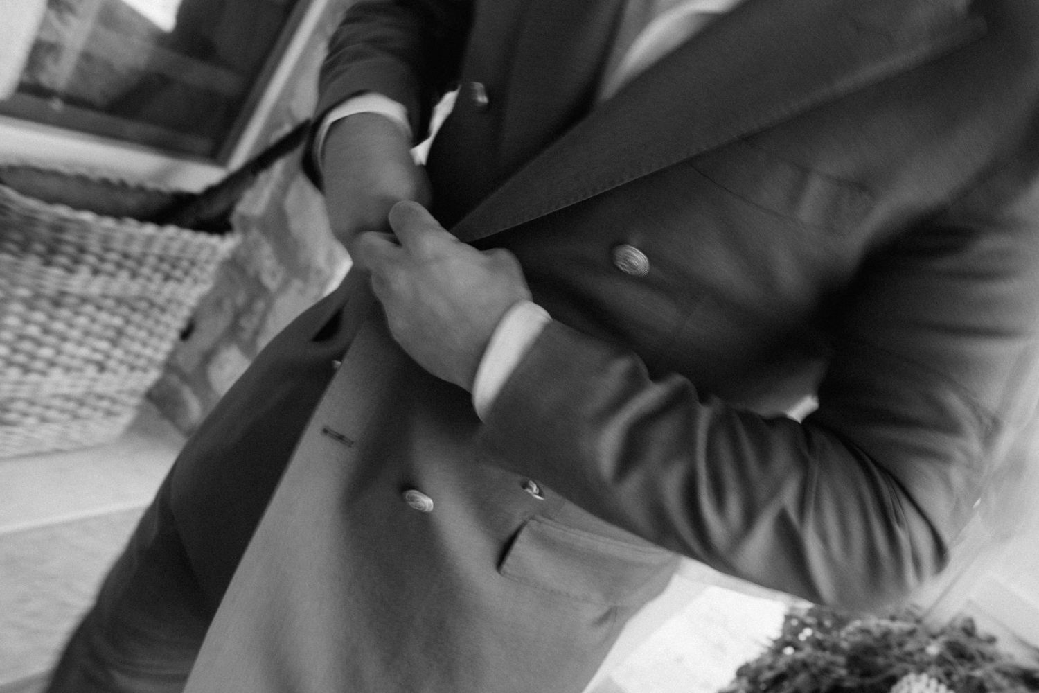 Man in a double-breasted suit adjusting his jacket, black and white photo.