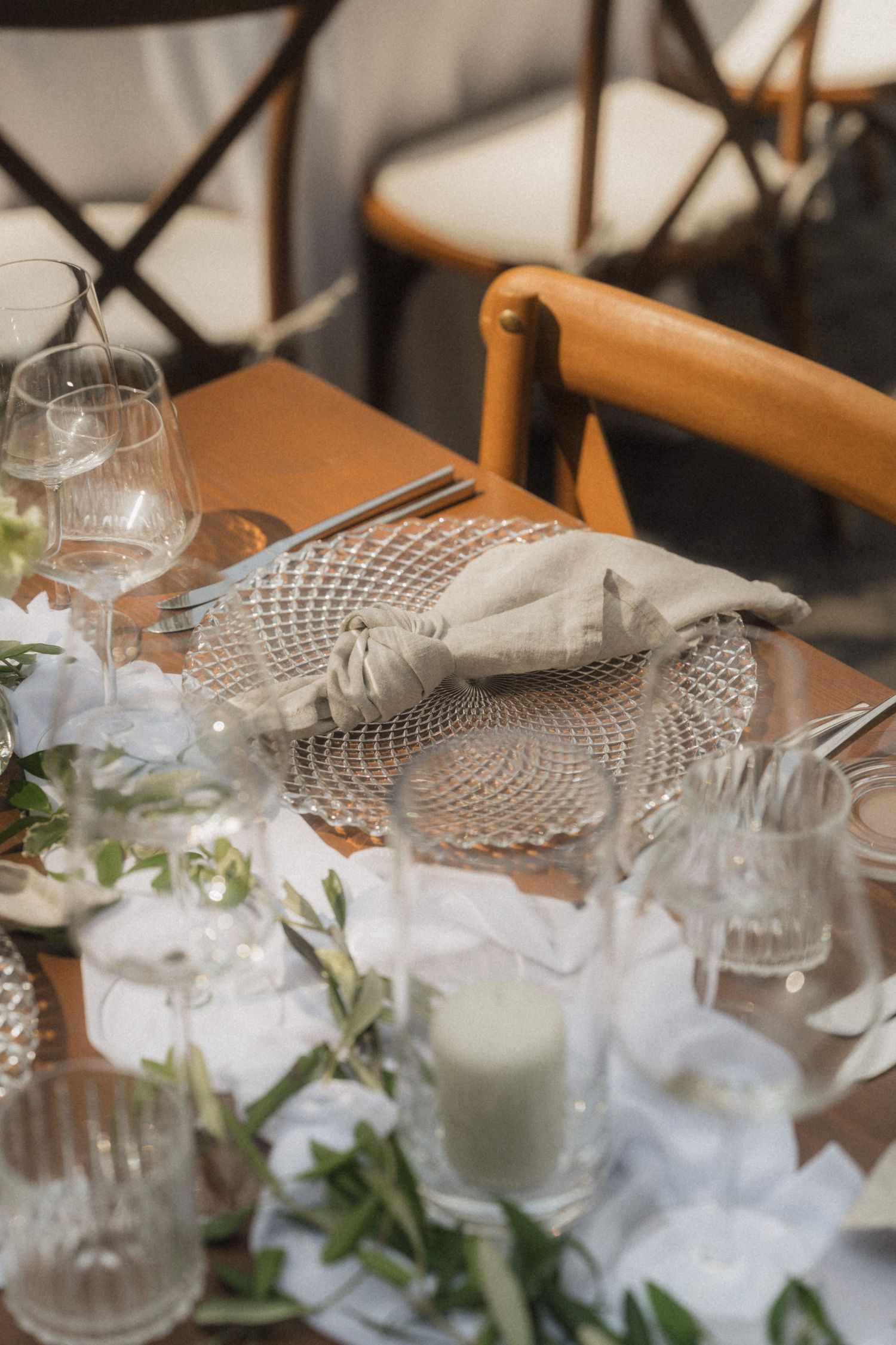 Elegant wedding table setting with crystal glassware, linen napkin, and white floral centerpiece.