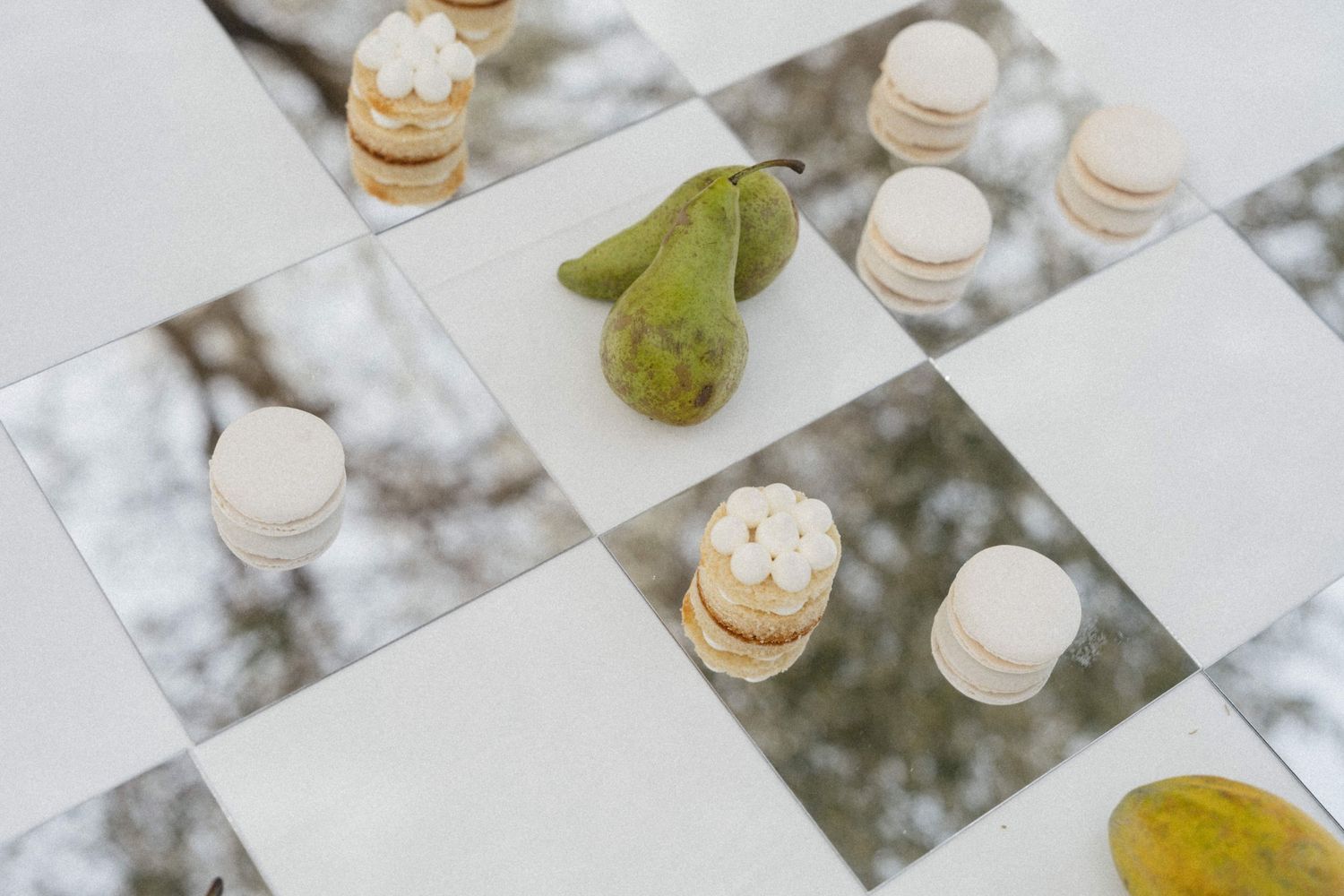 Elegant wedding reception table decor featuring mirror tiles, macarons, and fresh green pears.