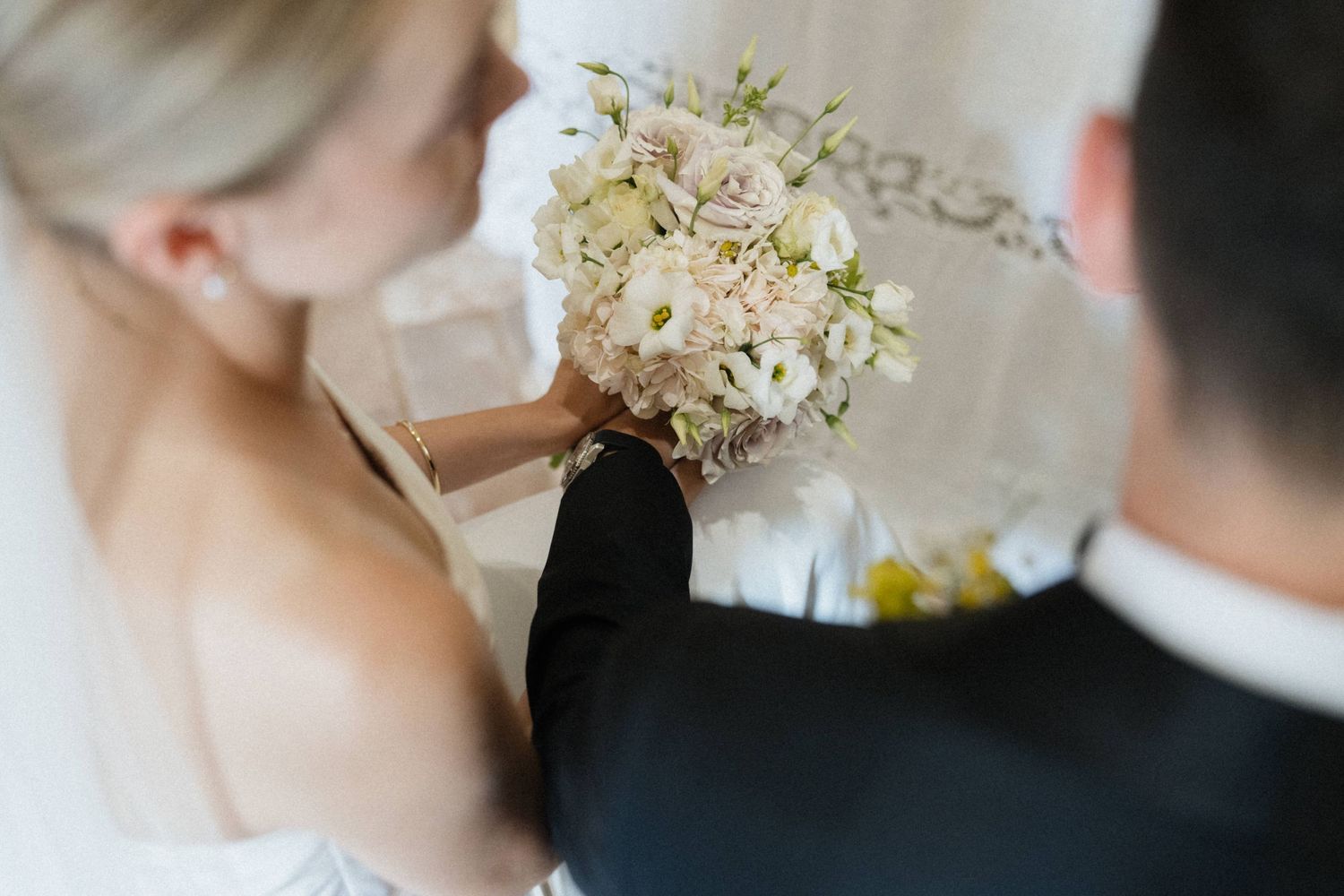 Bride and groom sharing a romantic moment with a white floral wedding bouquet on their wedding day.
