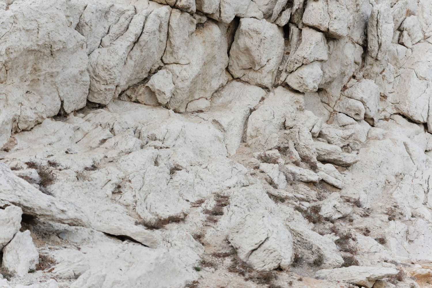 Close-up of rugged white limestone rock face with deep cracks and rough natural texture, ideal as a nature background.