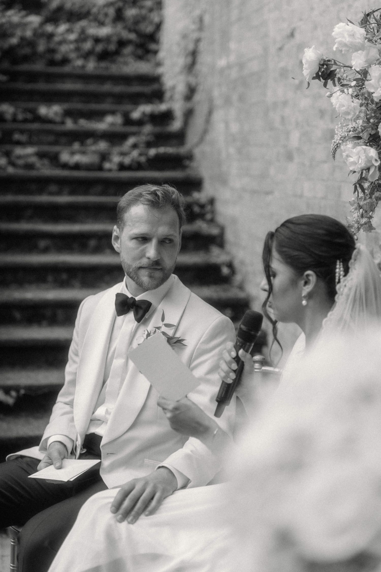 Black and white photo of bride reading vows to groom during intimate outdoor wedding ceremony.