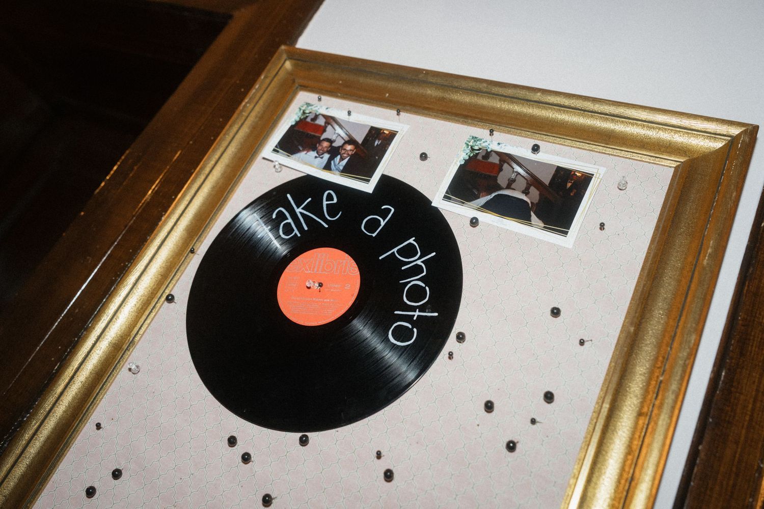 Vintage vinyl record in gold frame with take a photo sign and Polaroid photos for wedding photo booth.