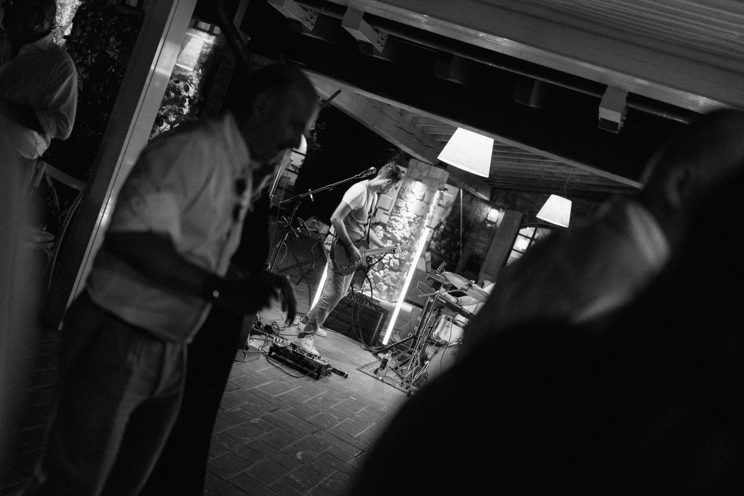 Black and white photo of a street food vendor preparing kebab meat on a vertical rotisserie at night.