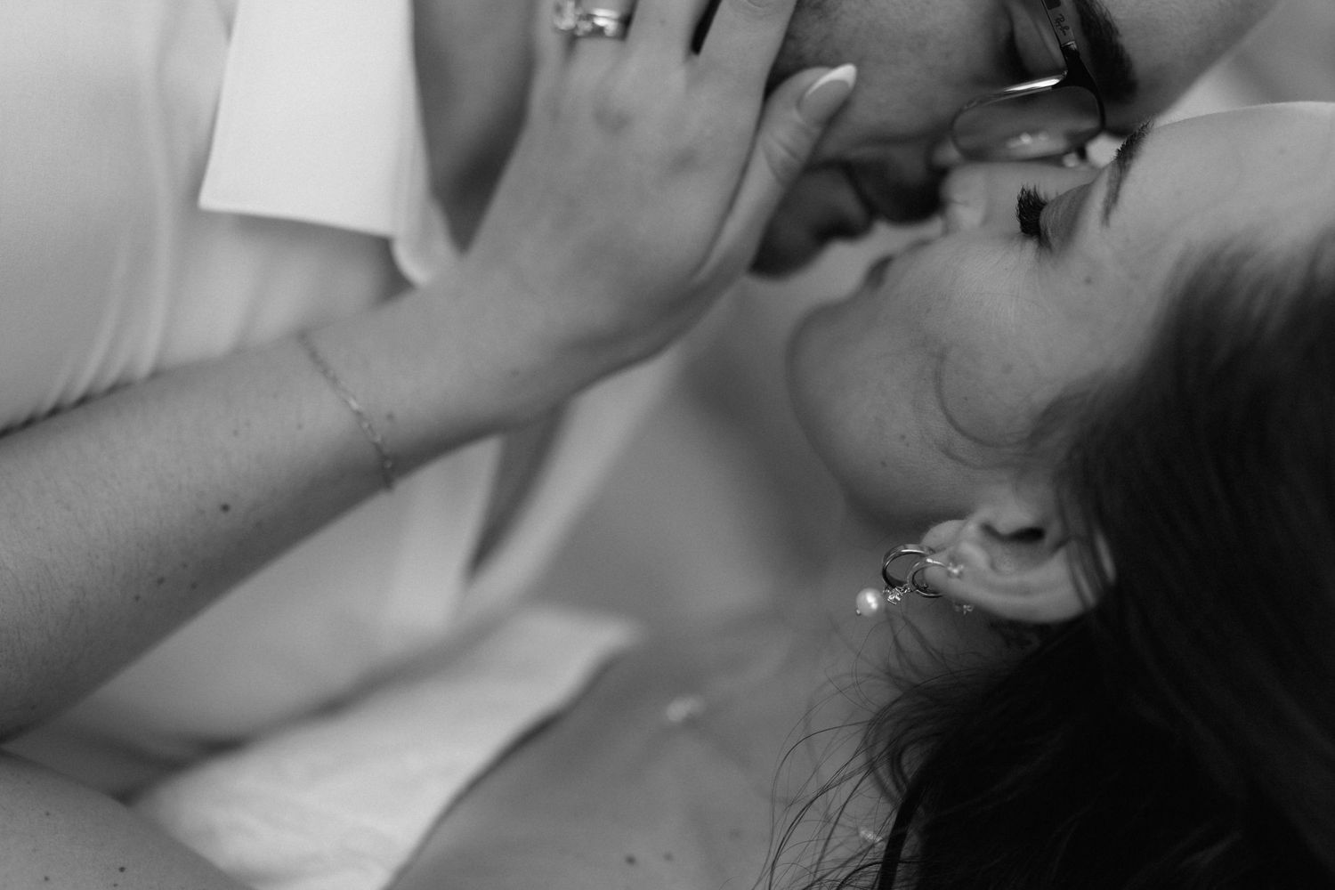 Black and white close-up of a couple sharing an intimate moment as a woman with an ear cuff gently touches her partner's face.