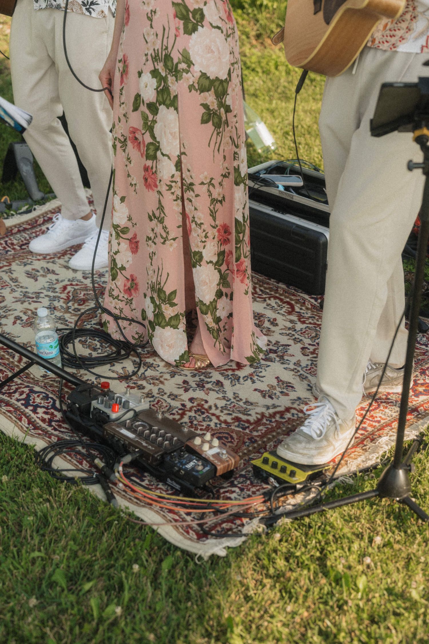 Close-up of musicians feet on vintage rug with guitar pedals and audio equipment at outdoor wedding.