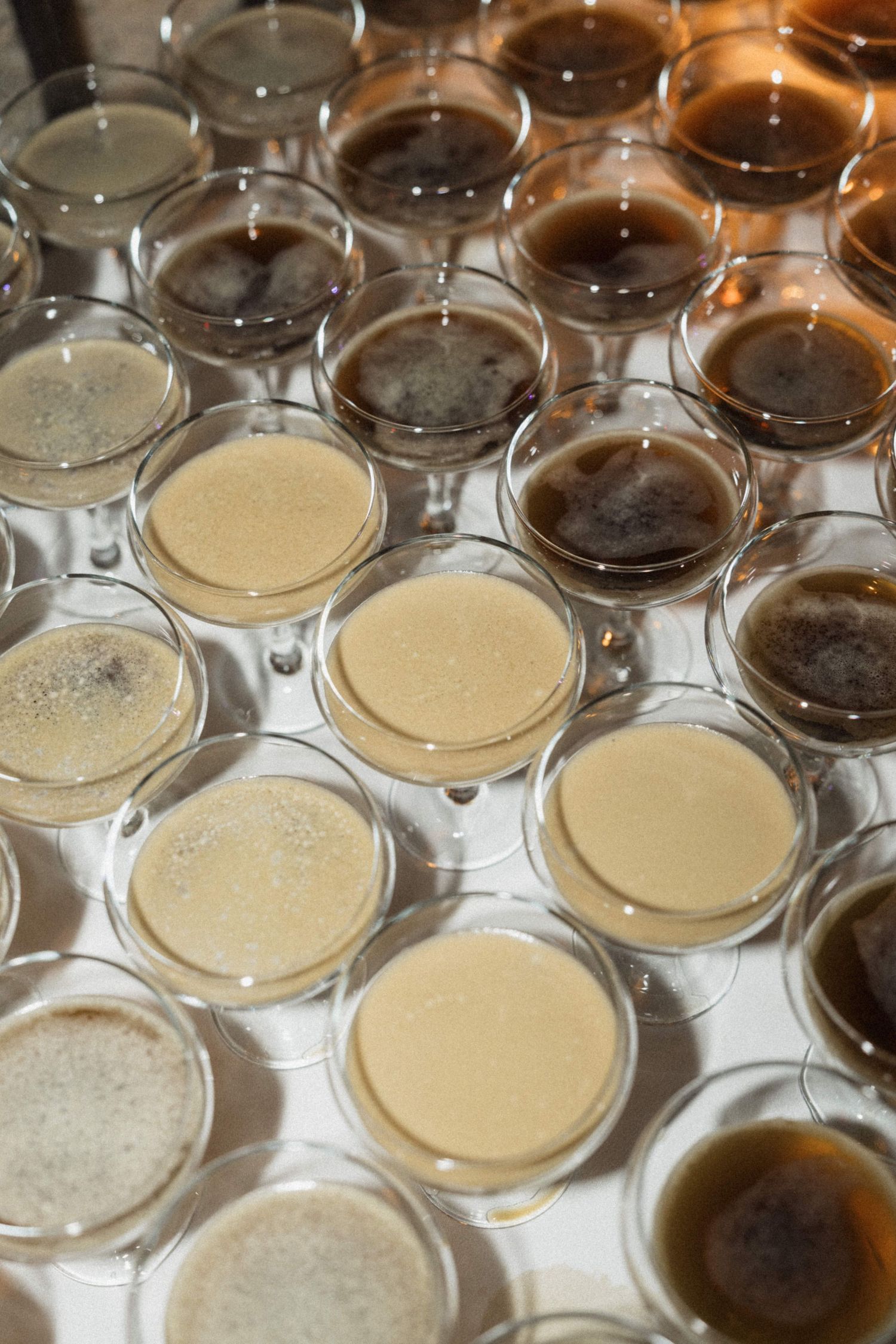 Rows of espresso martini cocktails and champagne glasses arranged on a tray at a wedding.