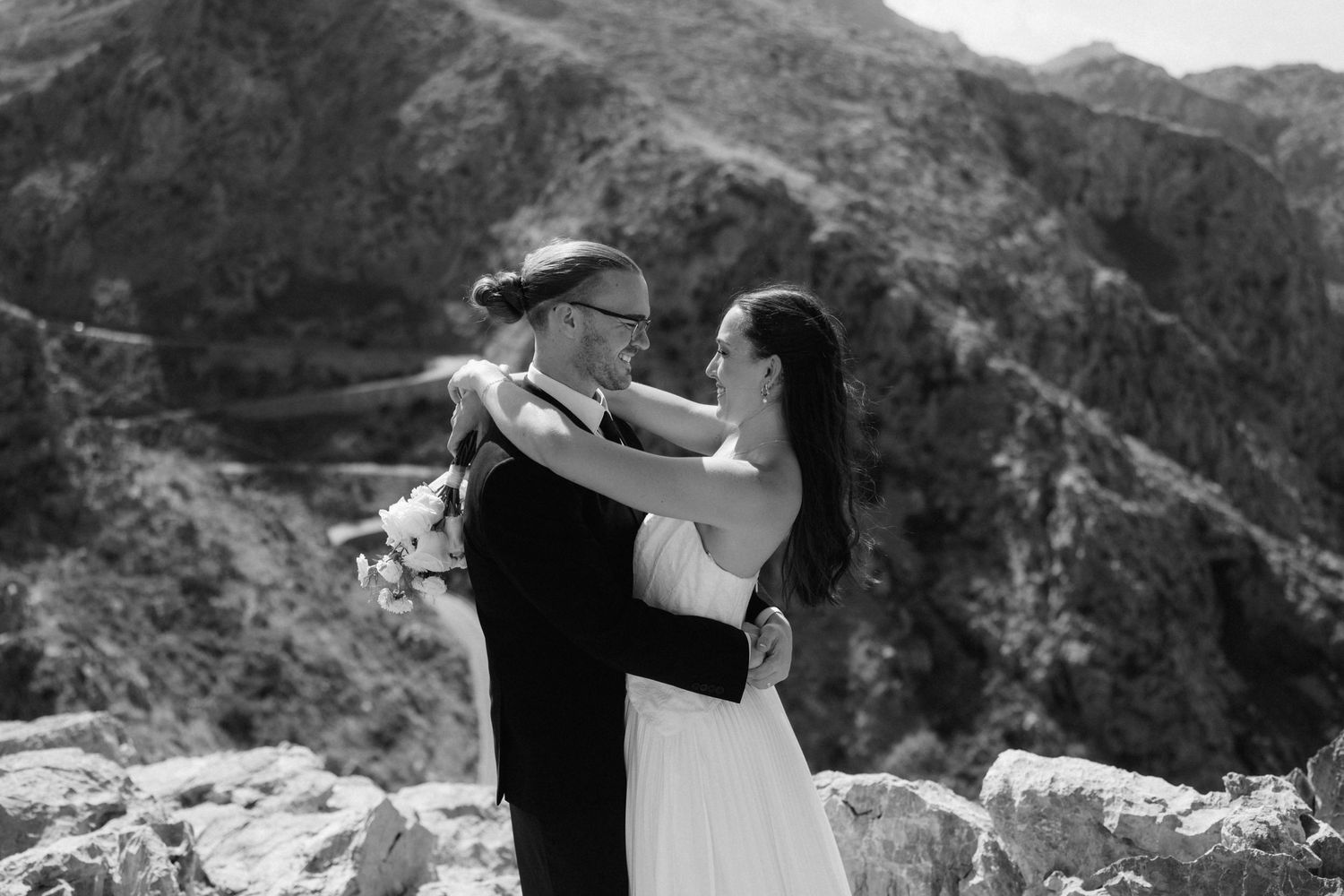 Black and white photo of a bride and groom embracing on a rocky mountain overlook during their elopement wedding.