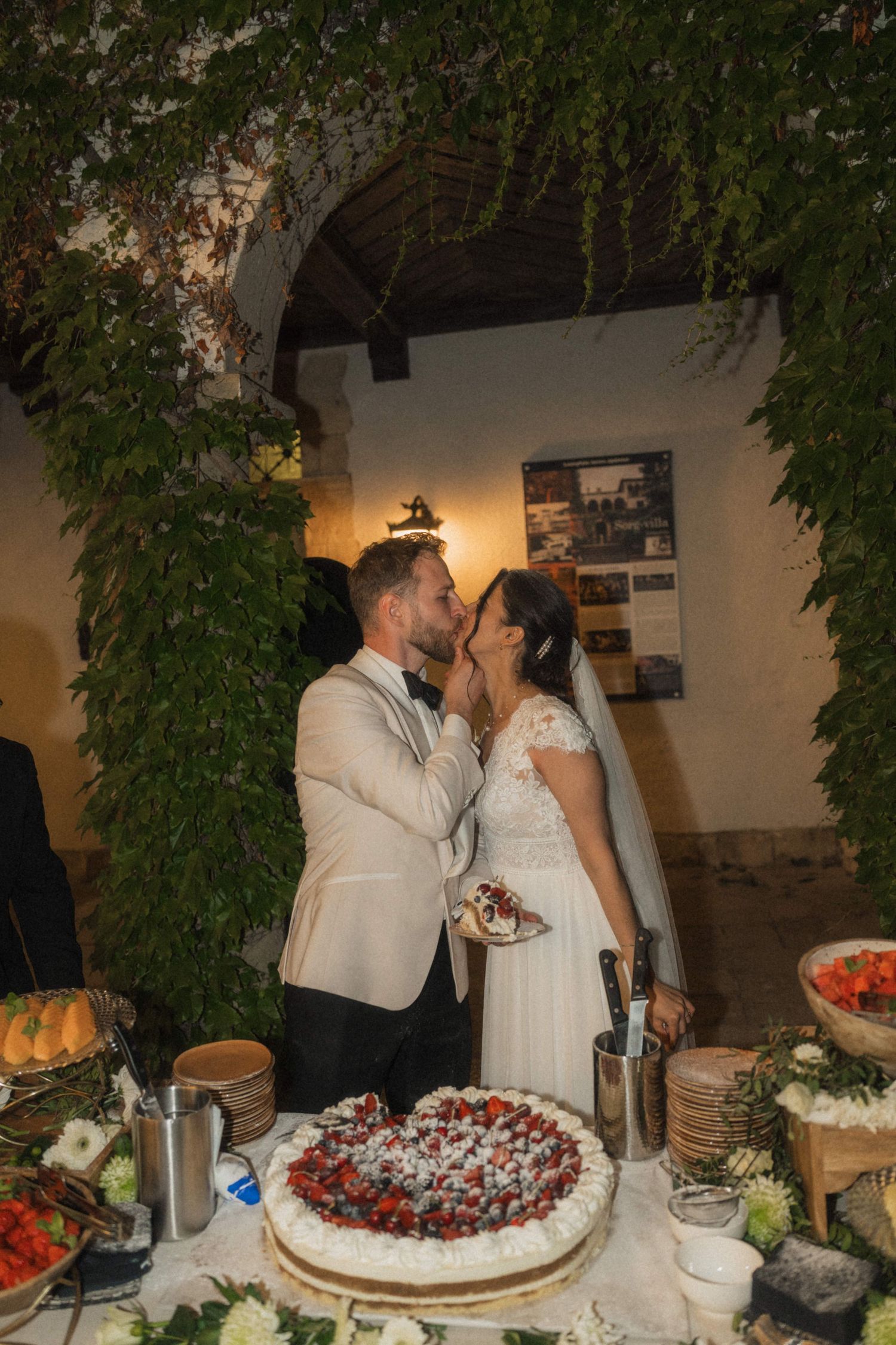 Bride and groom kissing over heart-shaped strawberry wedding cake at reception.