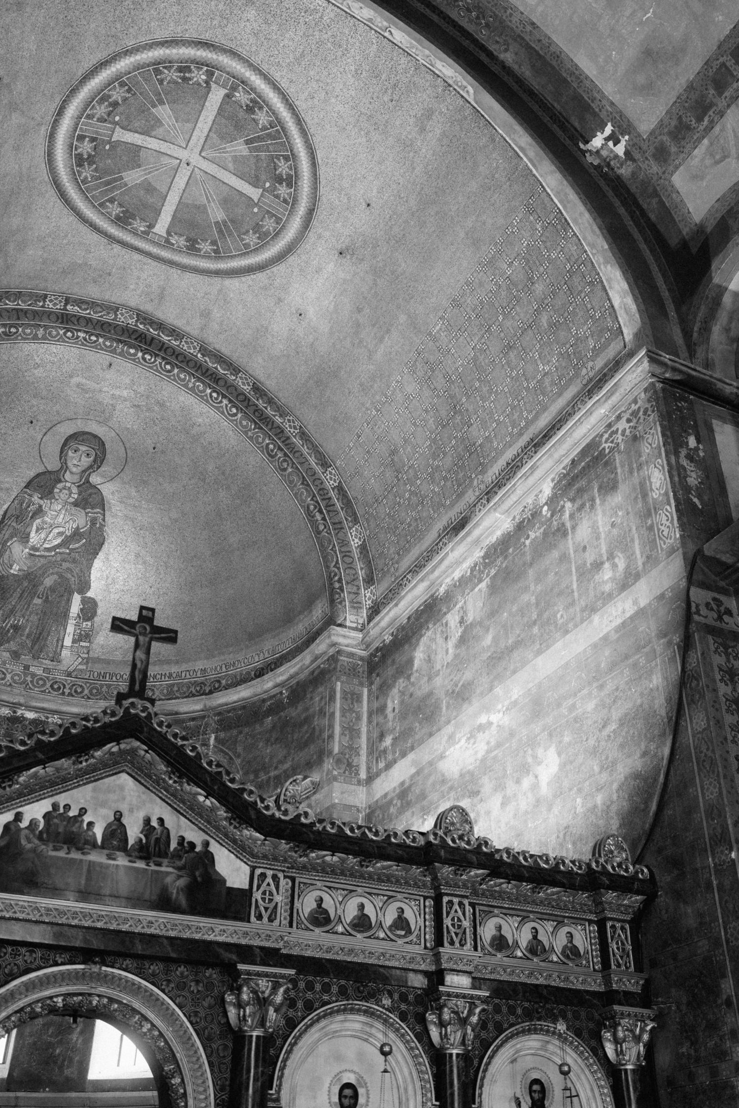 Black and white interior of Byzantine Orthodox church featuring ornate iconostasis and mosaic ceiling artwork.