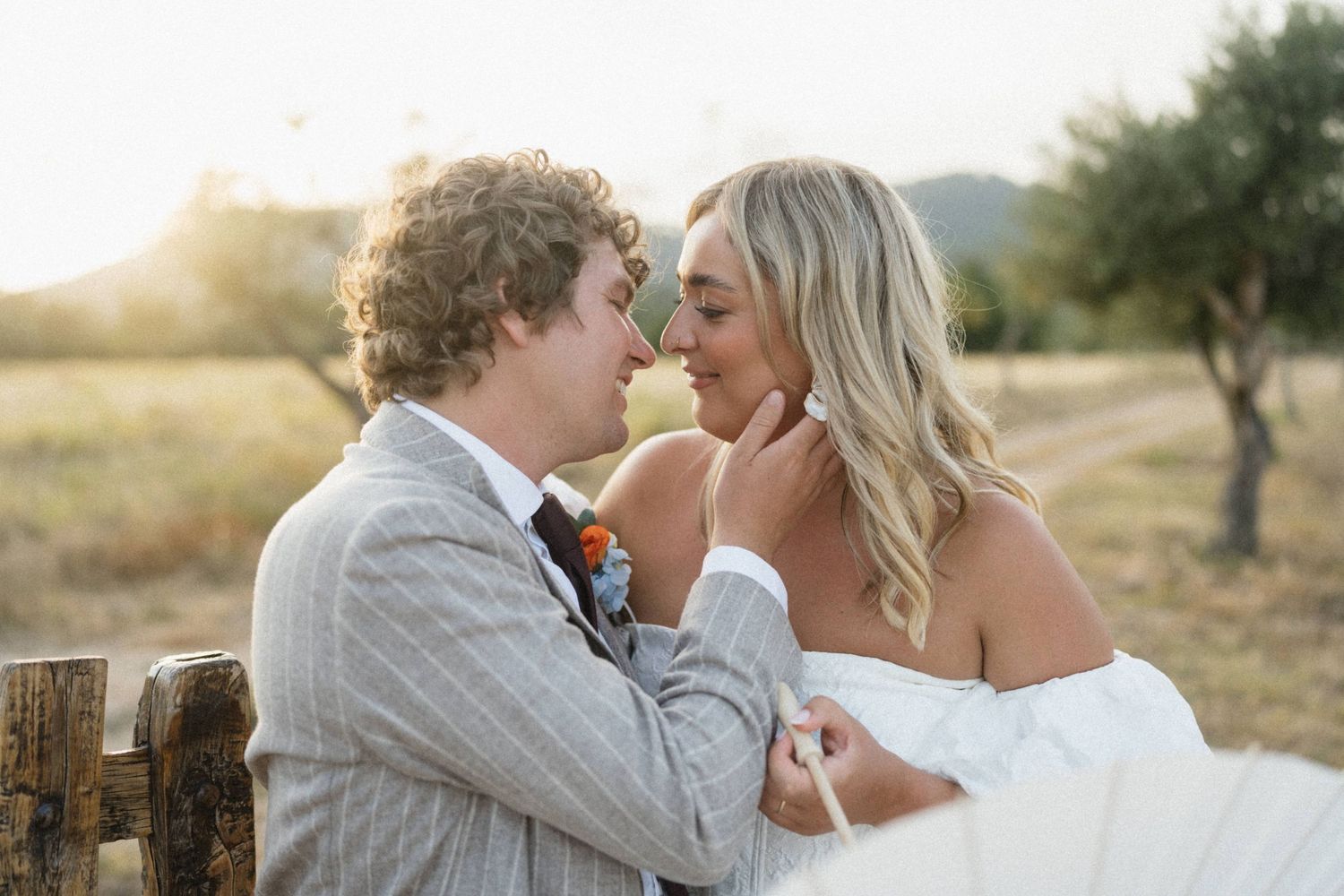 Romantic golden hour moment as newlyweds share an intimate embrace in a sunlit olive grove setting.