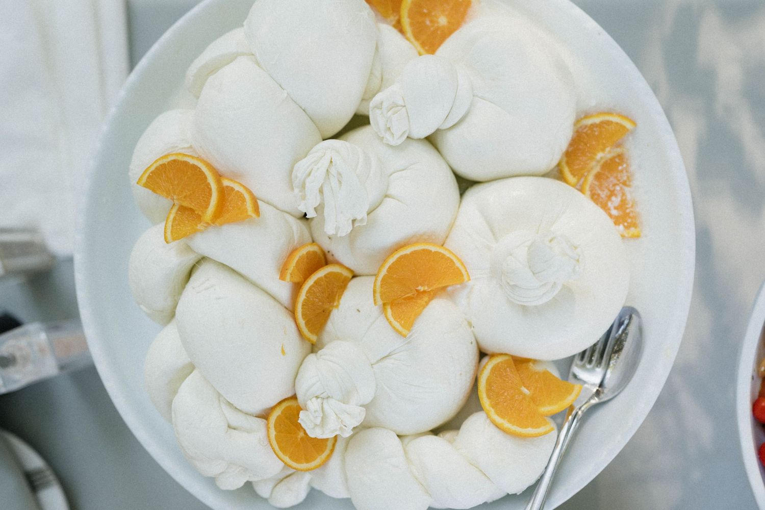 White meringue desserts topped with whipped cream and fresh orange slices arranged on a round white plate.
