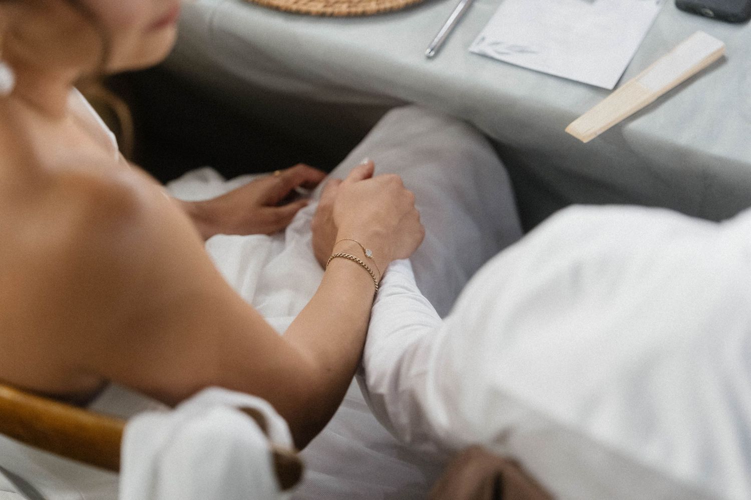 Two people in white robes holding hands while relaxing on a sofa, capturing a serene and intimate moment.