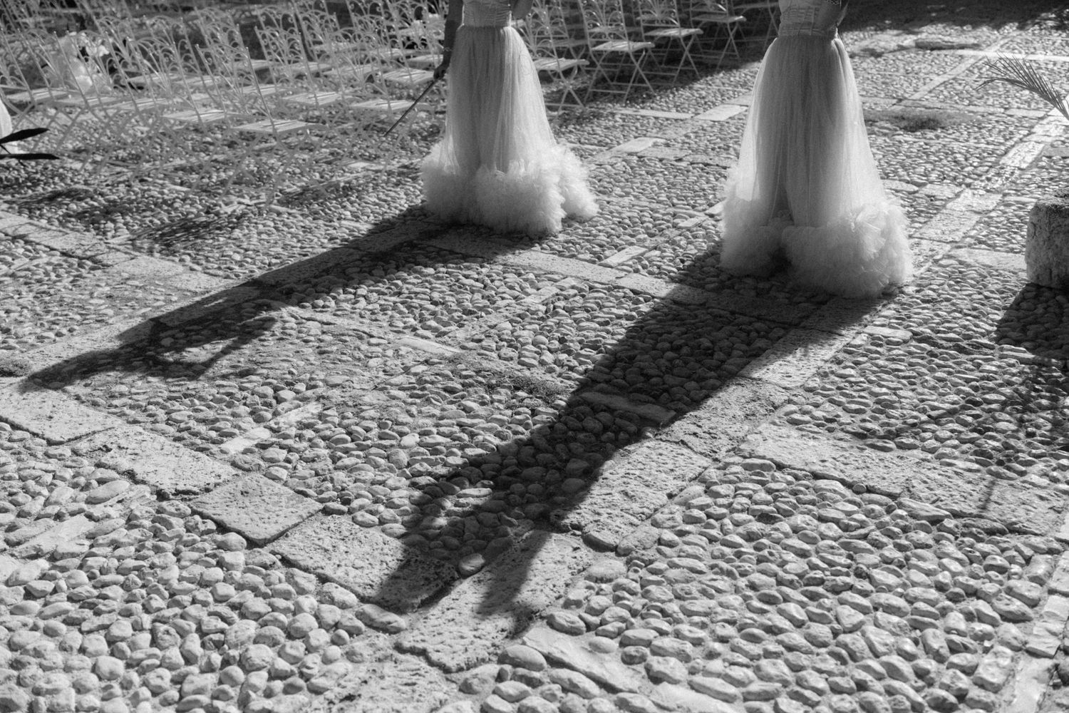 Black and white photo of wedding party shadows cast on cobblestone ground.
