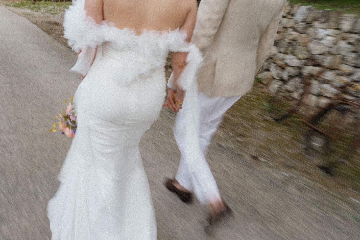 Motion blur shot of a bride and groom walking hand in hand down a path after their wedding ceremony.