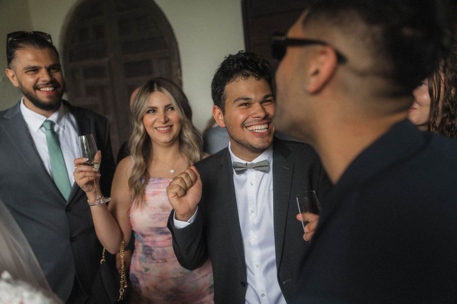 Wedding guests smiling and socializing with champagne glasses at a joyful reception celebration.