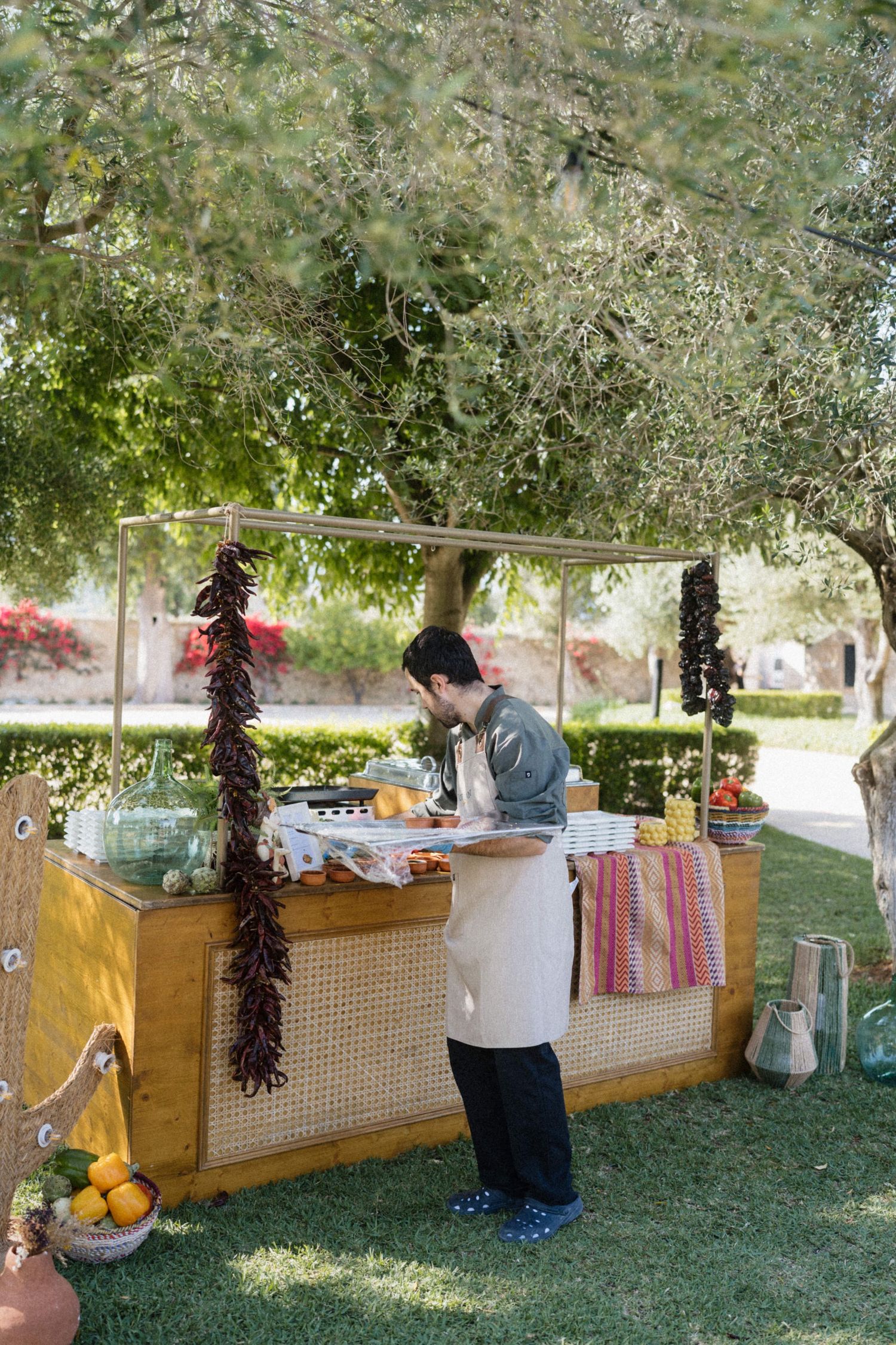 Catering staff preparing food at a rustic outdoor wedding buffet station decorated with dried chilis.