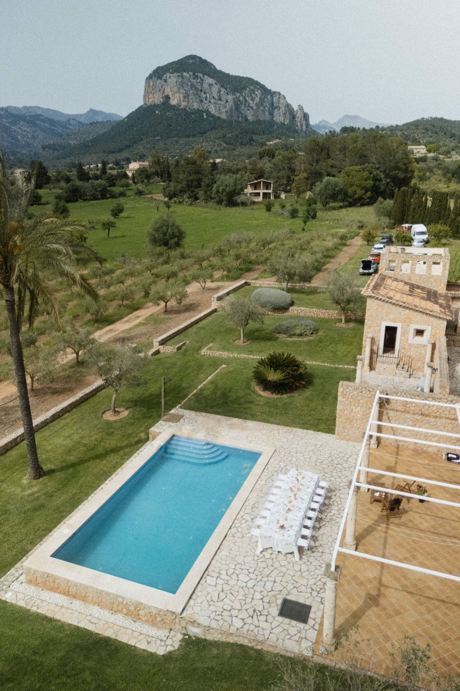 Aerial view of luxury villa with pool, manicured gardens, and dramatic mountain backdrop in Mallorca.