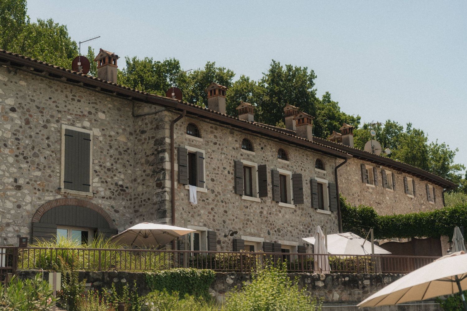 Historic stone villa with arched windows and lush greenery, a rustic Italian wedding venue under clear blue skies.