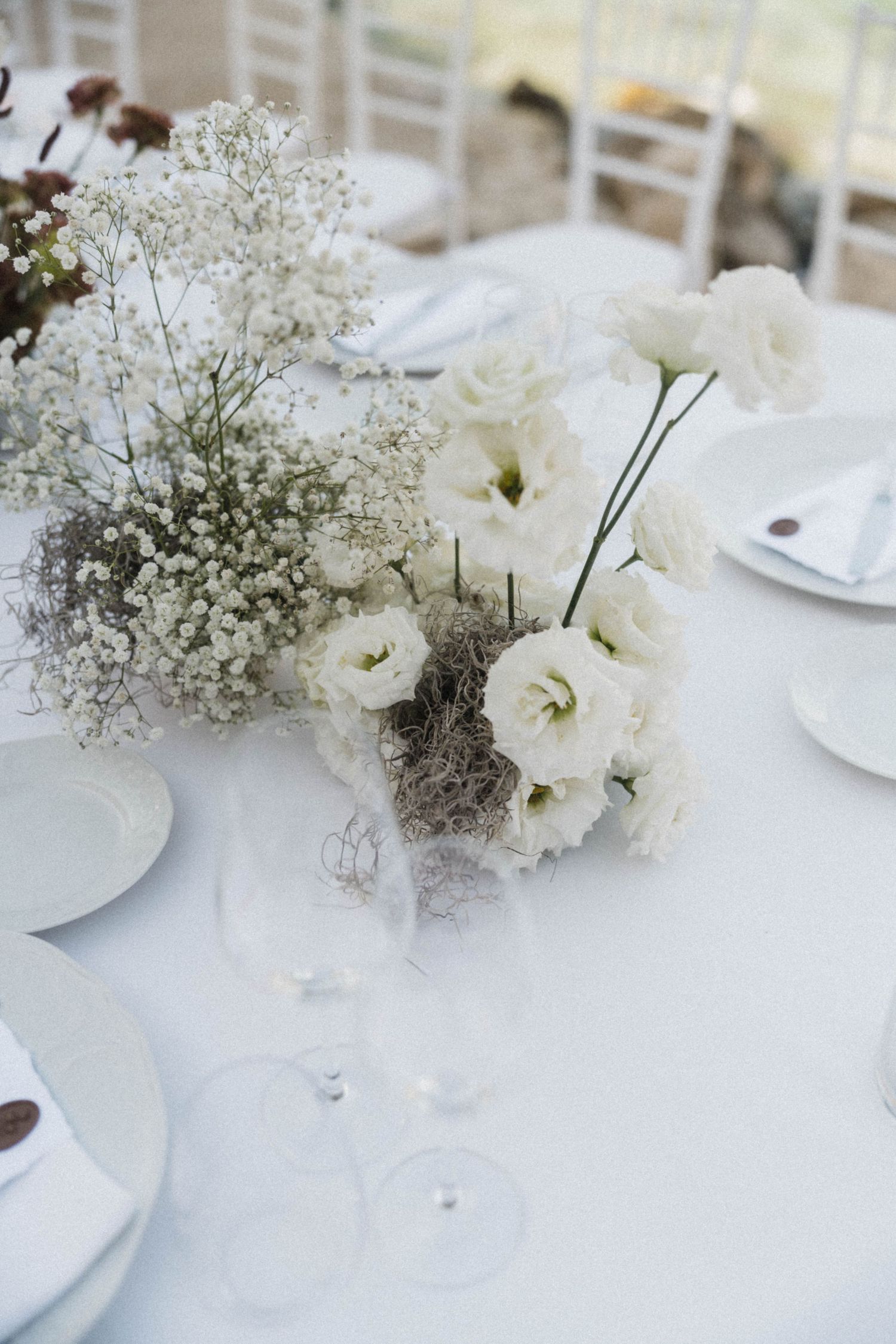 White wedding table centerpiece featuring lisianthus and baby's breath flowers with crystal glassware.