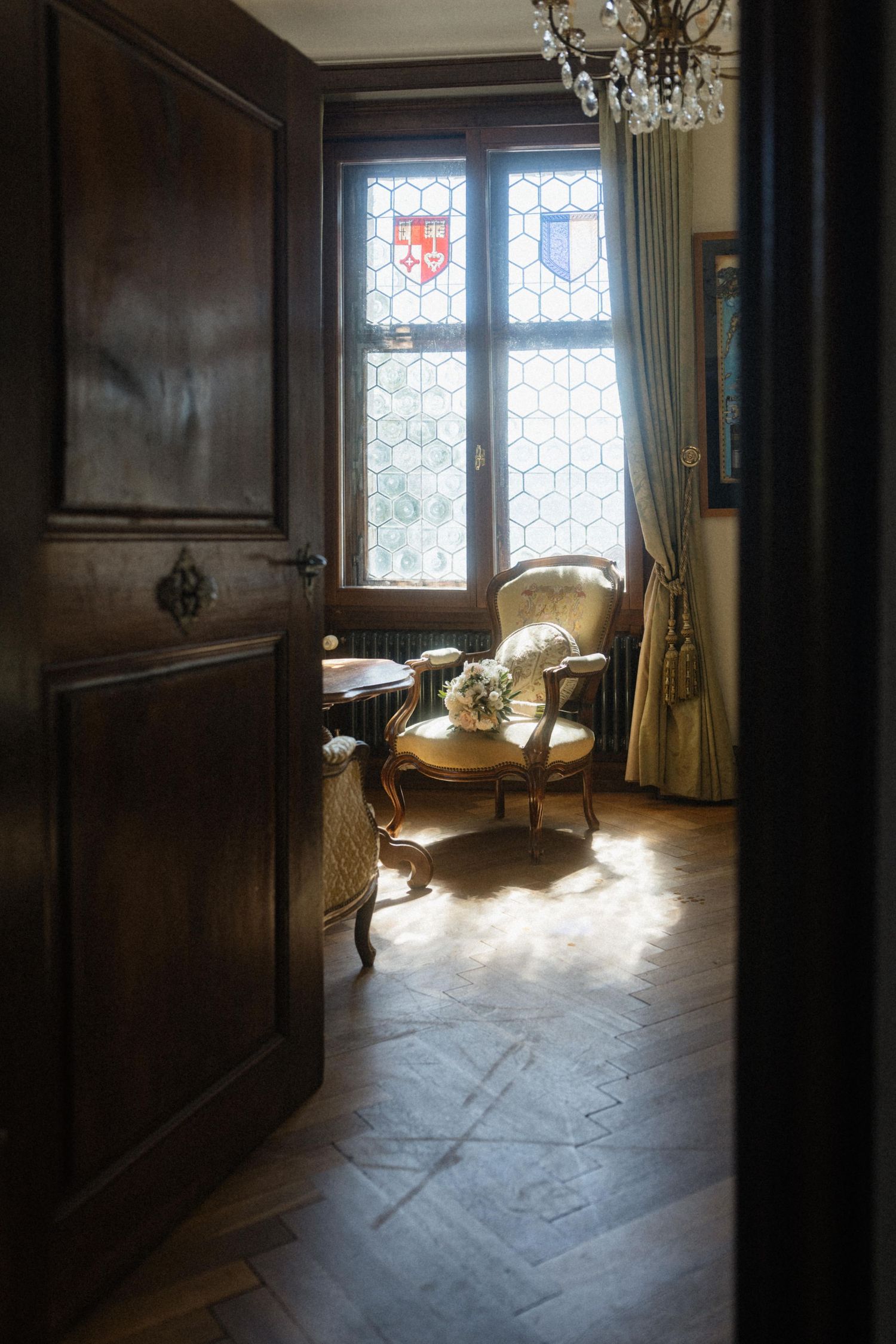 Elegant vintage room with stained glass windows, ornate armchair, and dark wood paneling in a historic manor.