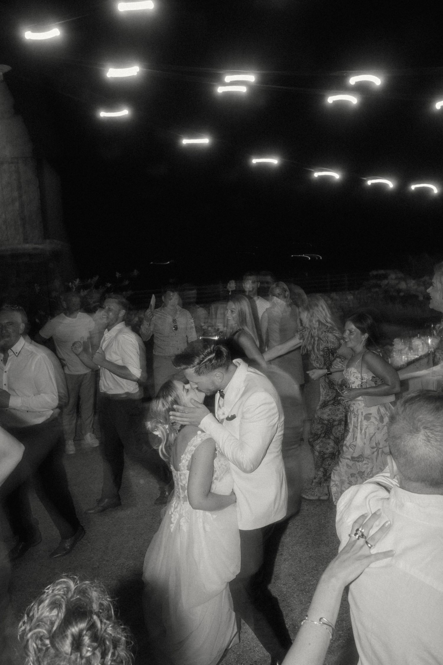 Bride and groom sharing first dance in black and white photo at evening wedding reception.