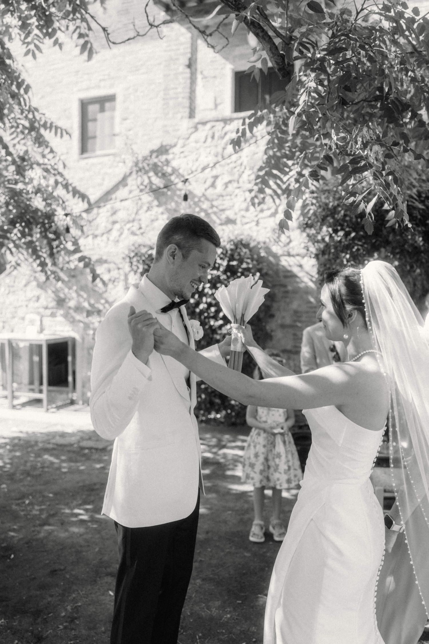 Black and white photo of bride and groom sharing tender moment outdoors at rustic wedding venue.
