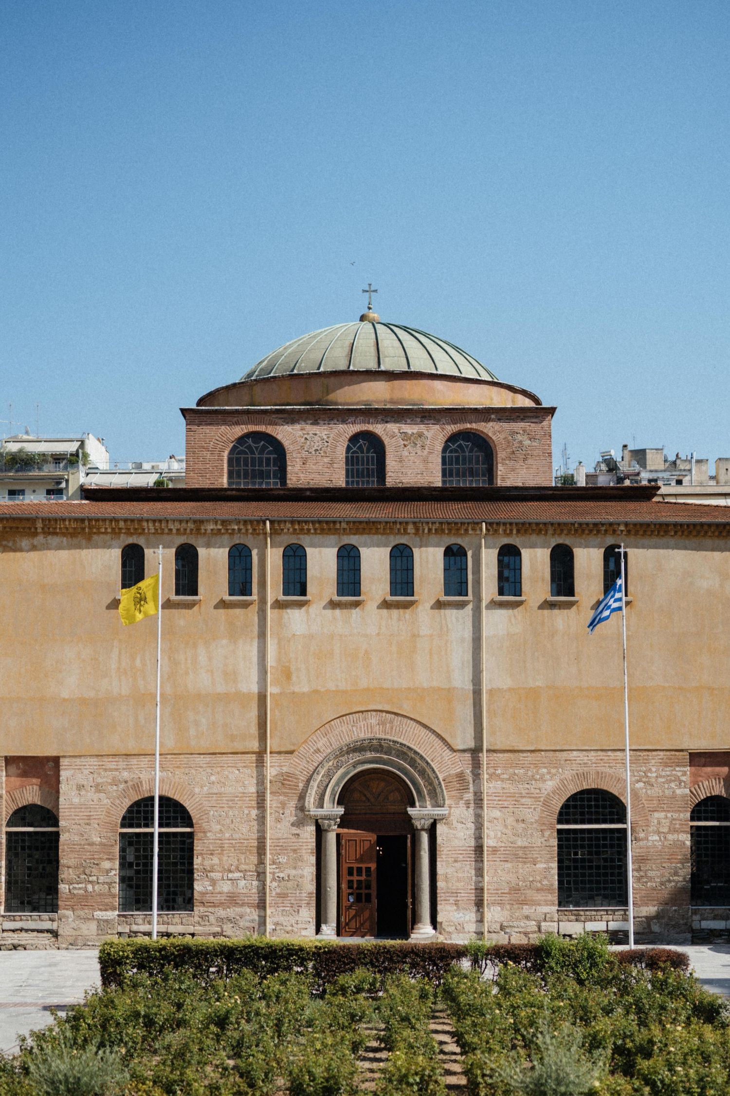 Historic Byzantine church with dome and Greek flag in Thessaloniki, Greece.