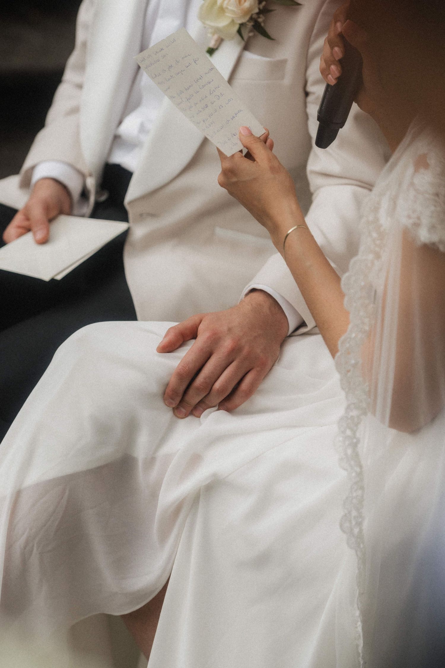 Close-up of bride and groom holding hands during wedding ceremony while reading vows.