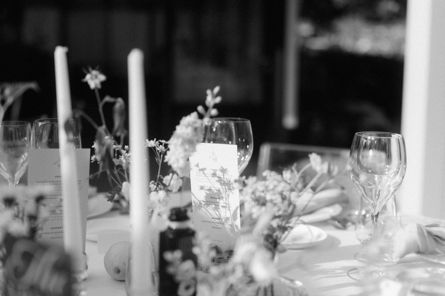 Black and white elegant wedding table setting with tall candles, floral arrangements, and crystal glassware.