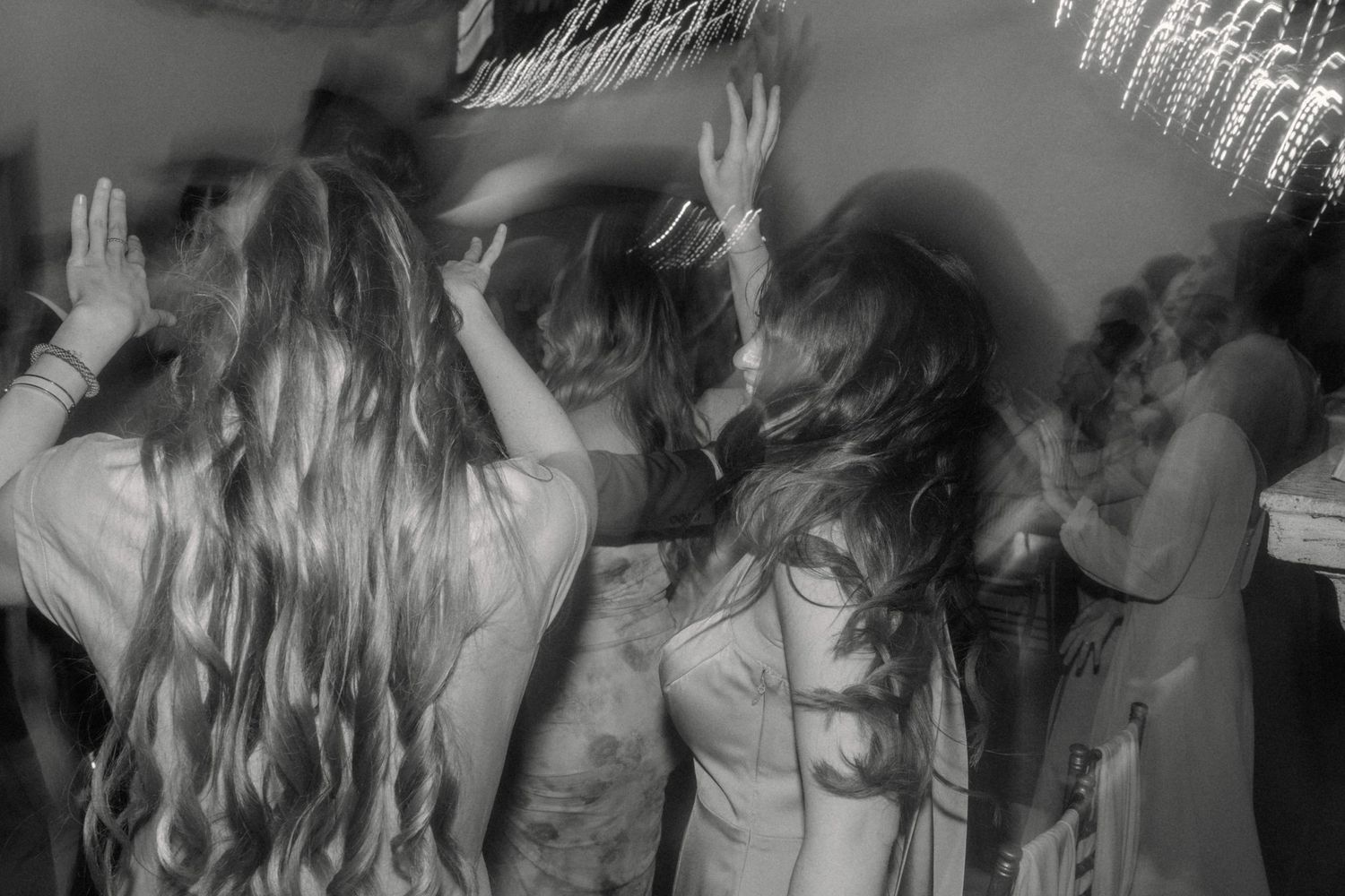 Black and white motion blur photo of wedding guests dancing energetically on the dance floor.