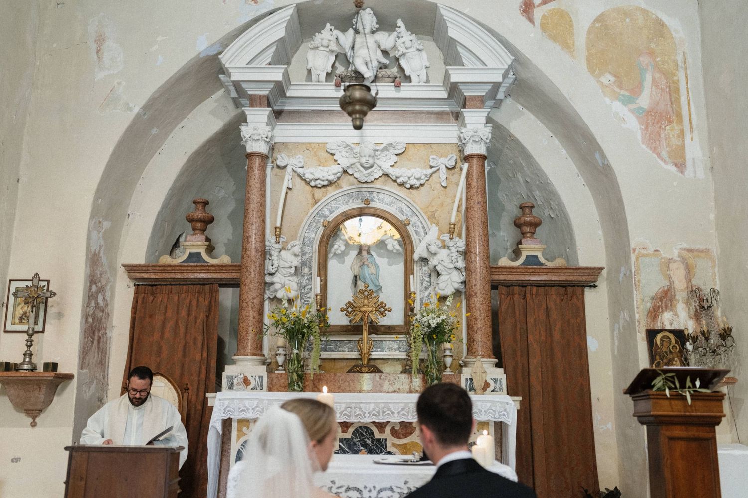 A bride and groom stand at the altar of an ornate church during their wedding ceremony.