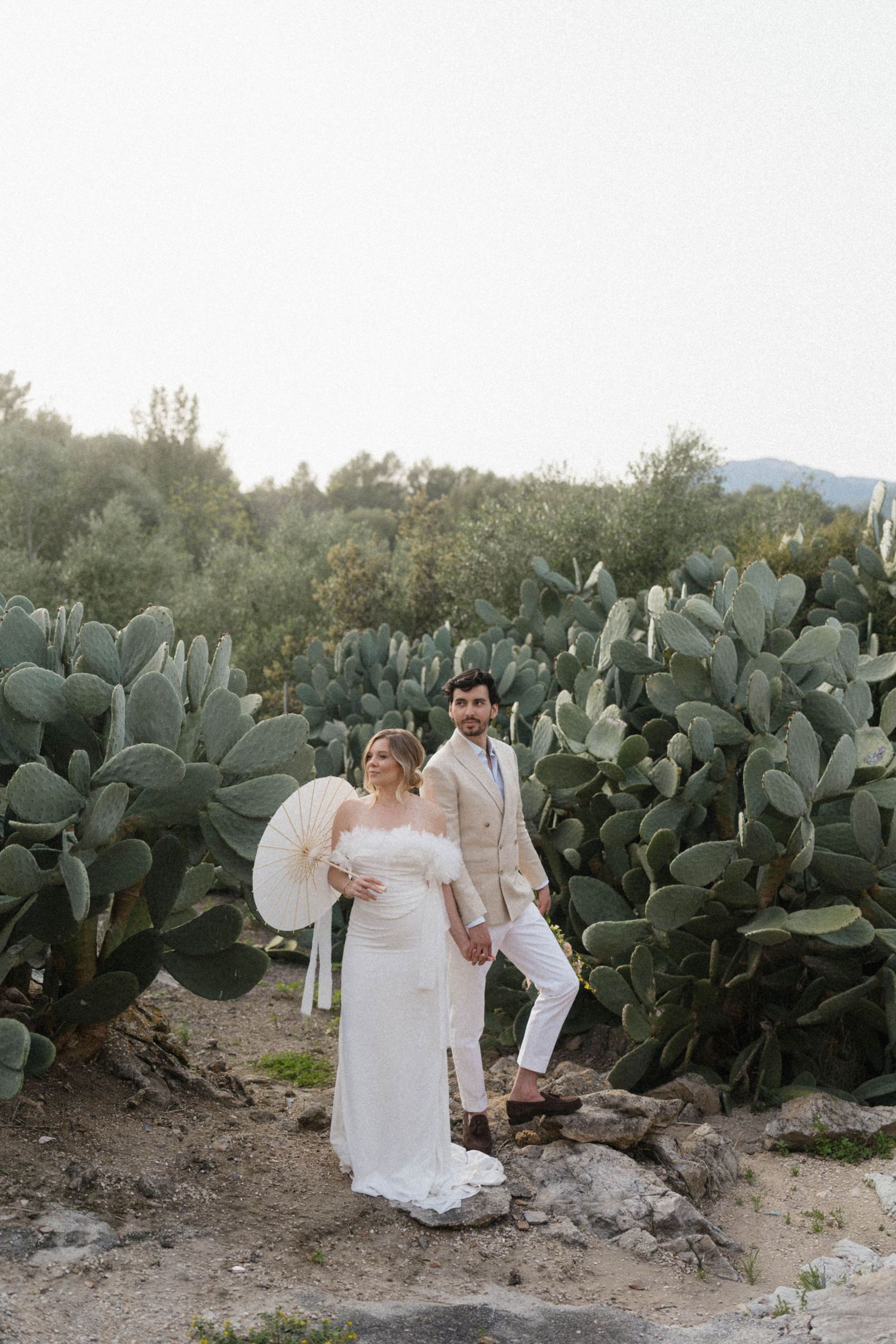 Bride and groom pose together in front of large prickly pear cactus garden at outdoor wedding venue.
